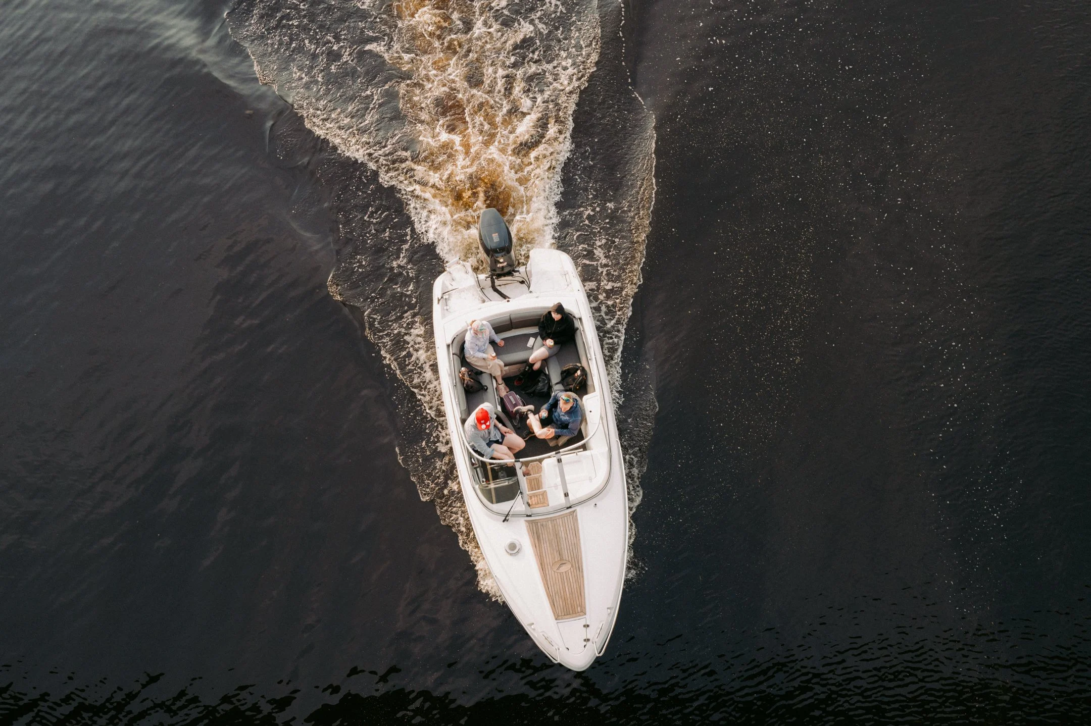 Vene matkustajineen ajamassa vedessä, katsottuna ylhäältä päin.