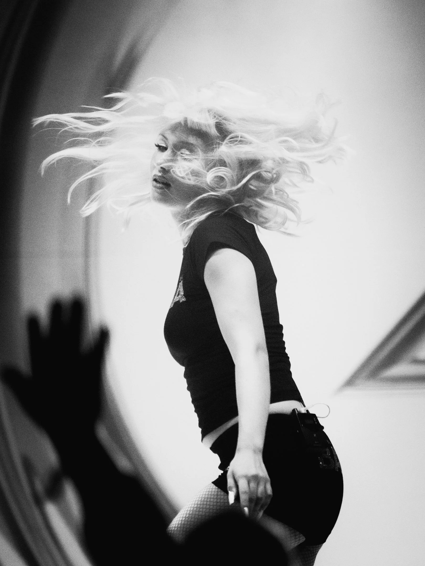 Mustavalkokuva naisesta, jolla pitkät, vaaleat hiukset, hän tanssii tai esiintyy ja haalea tausta