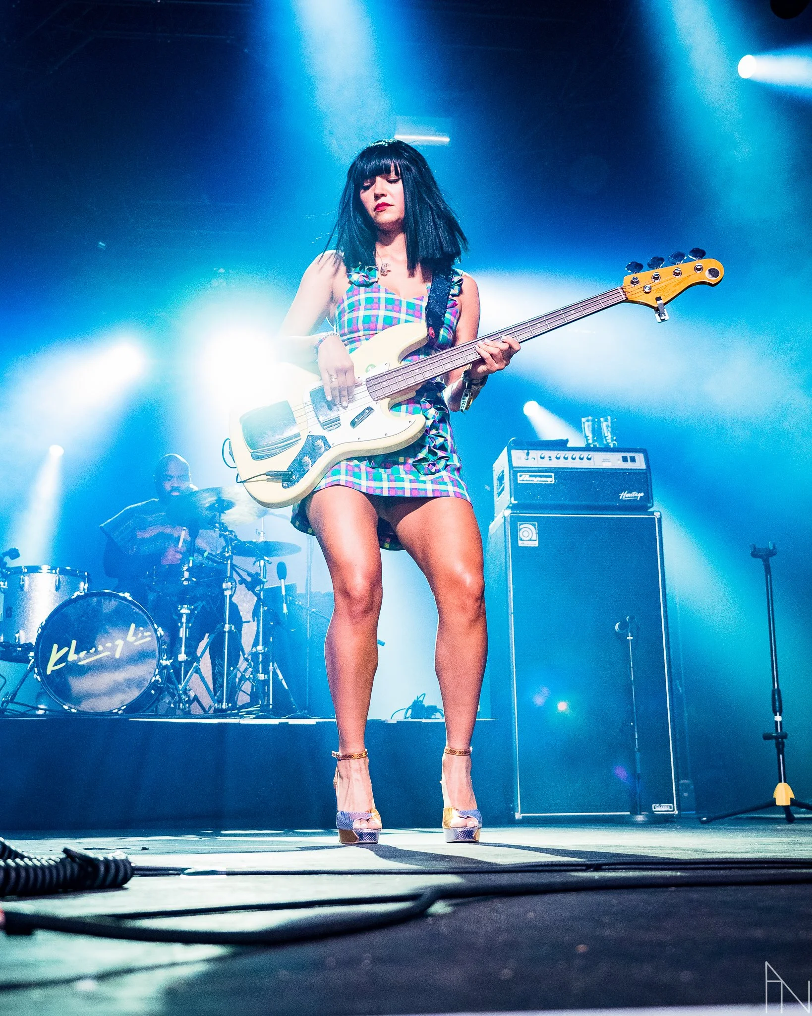 Nainen soittaa bassokitaralla esiintymislavalla, takana rumpali ja musiikkivahvistin. Khruangbin, Laura Lee Ochoa, legs, Flow Festival Helsinki.