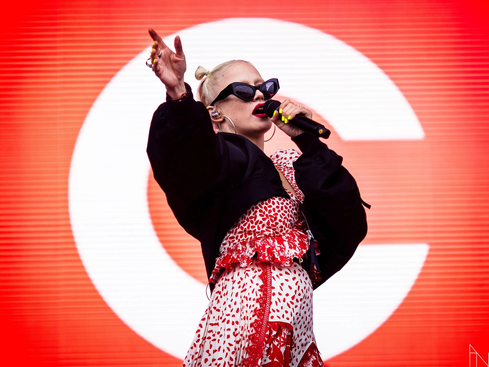 Kuuluisa naisartisti, Chisu, esiintymässä lavalla, taustalla suuri punainen ja valkoinen taustakuva.