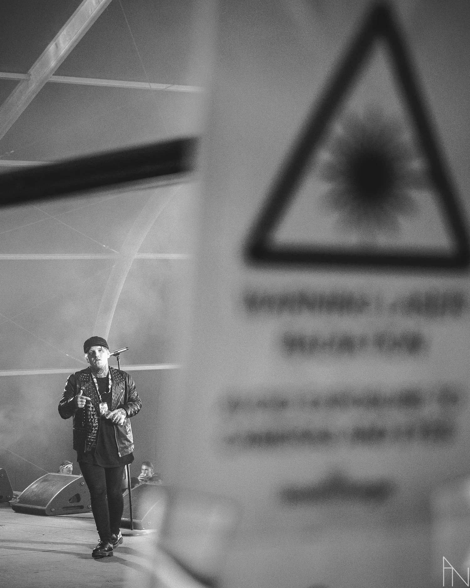 Räppäri kuvattu lavalta Blockfesteilla. Etualalla on varoitusmerkki.