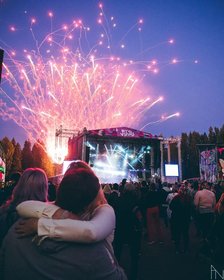 Yleisö katsomassa konsertin esiintymistä ulkona ilta-aikaan, taustalla ilotulitteita taivaalla. Nuoripari suutelee etualalla. Provinssi, Seinäjoki.