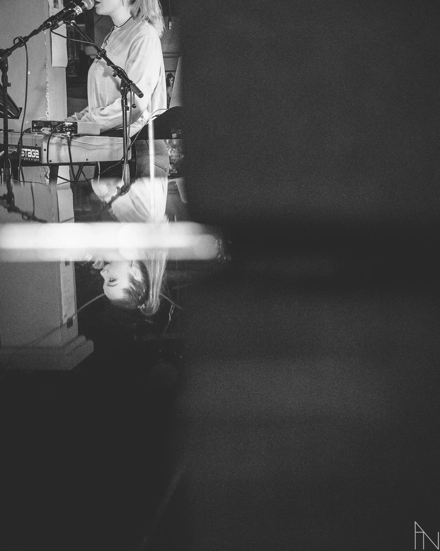 Mustavalkoinen kuva naisesta laulamassa. Heijastus pianon kannesta.