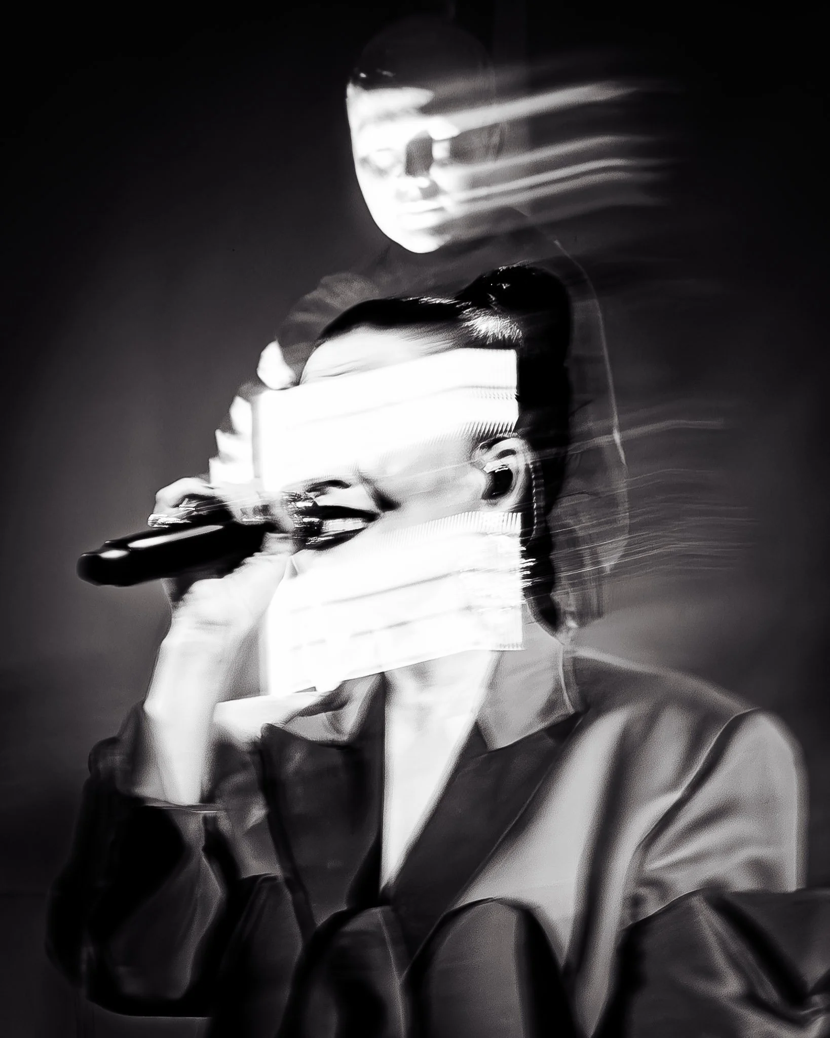 Mustavalkoinen kuva naisesta, joka laulaa mikrofonin kanssa, mutta kuva on erittäin epätarkka ja epäsymmetrinen, mikä aiheuttaa liikekuvioita ja teknisistä ongelmista johtuvia vääristymiä.