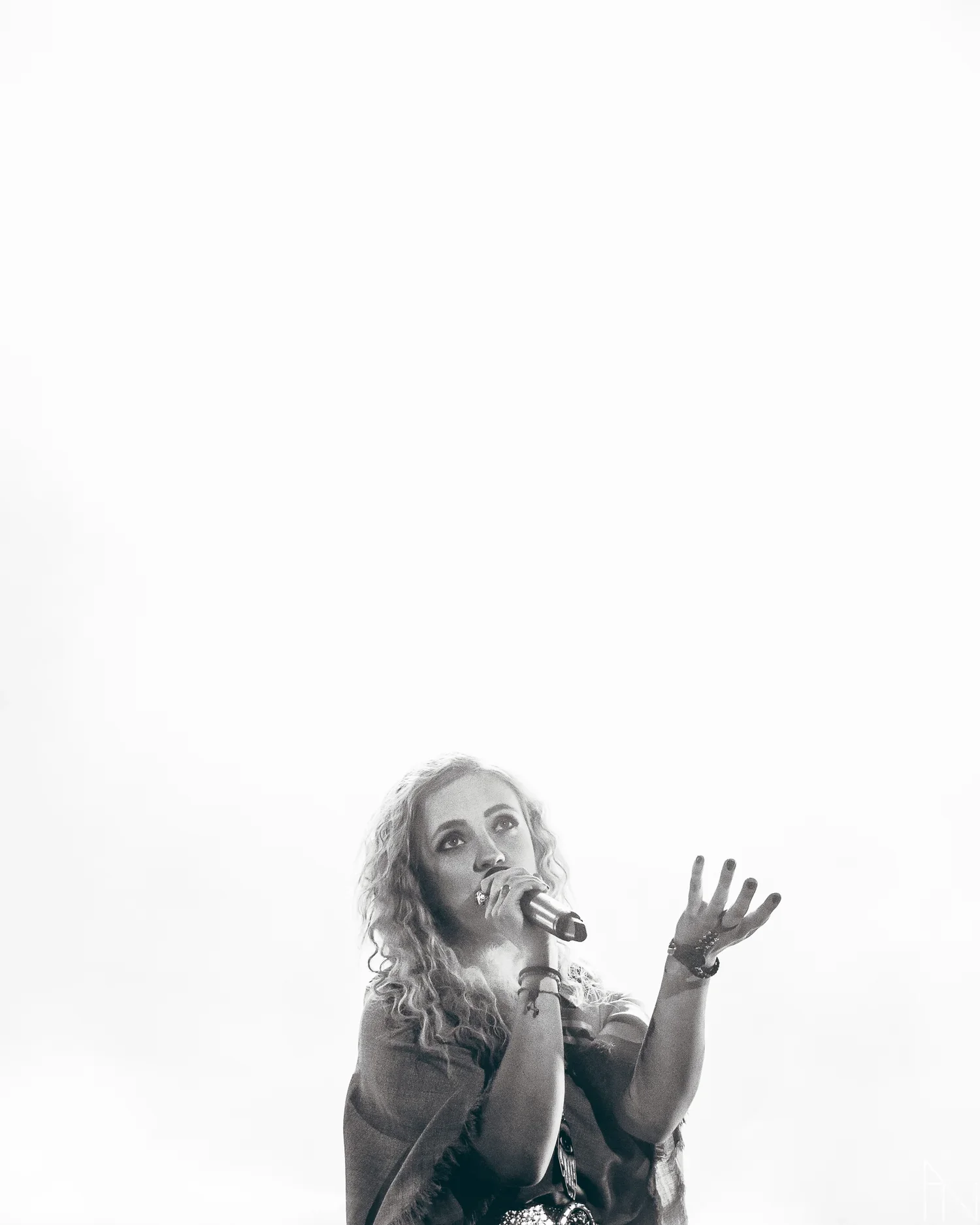 Mustavalkoinen kuva naisesta, joka laulaa mikrofonilla ja tekee näyttäviä kädenliikkeitä.