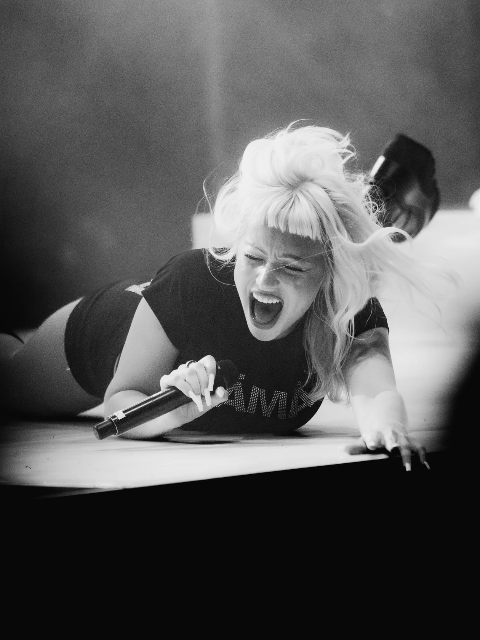 Naista esittää voimakkaasti yöllä, makaa lattialla ja huutaa mikrofoni kädessään.