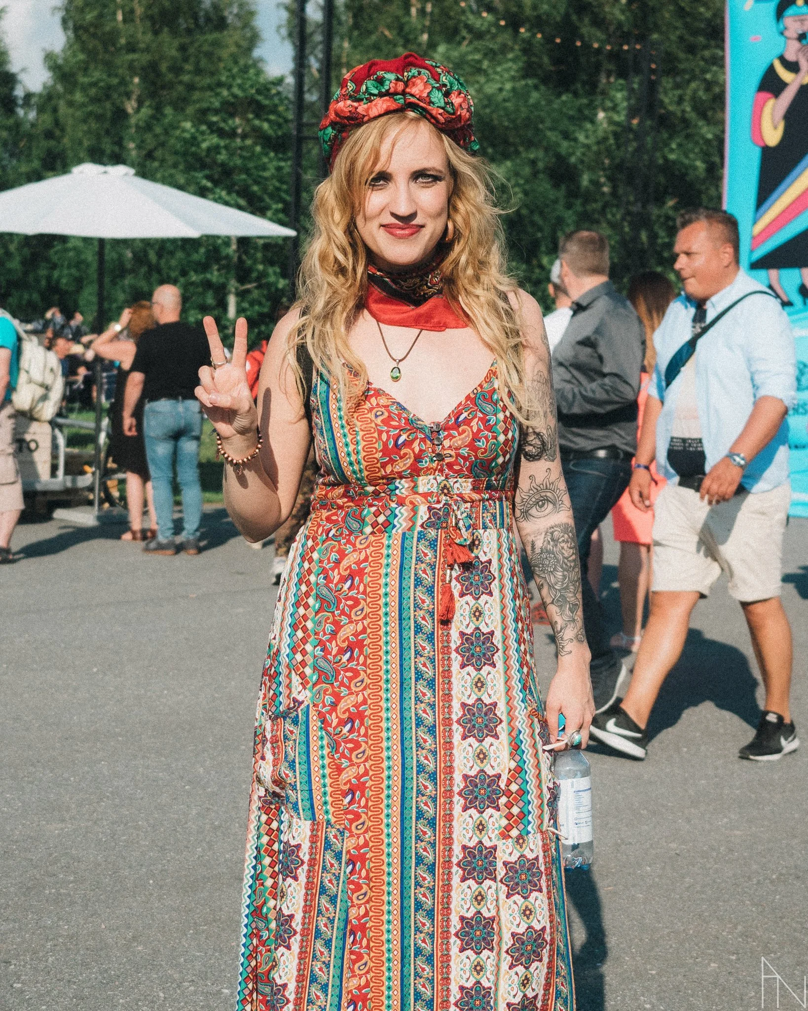 Nuori nainen hymyilee ja näyttää peace-merkkiä. Hänellä on pitkät, vaaleat hiukset ja värikäs, boheemi asu. Elli Haloo Pori Jazz.