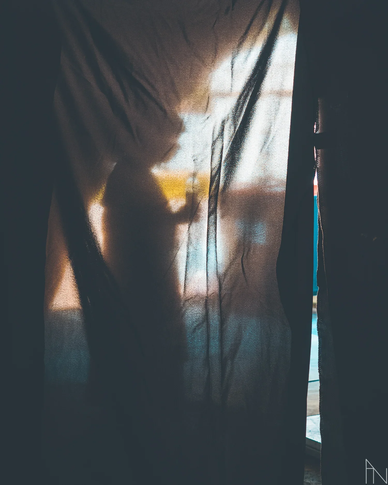 Valo tulvii verhon läpi ja verhon takana silhuetti auringonlaskussa.