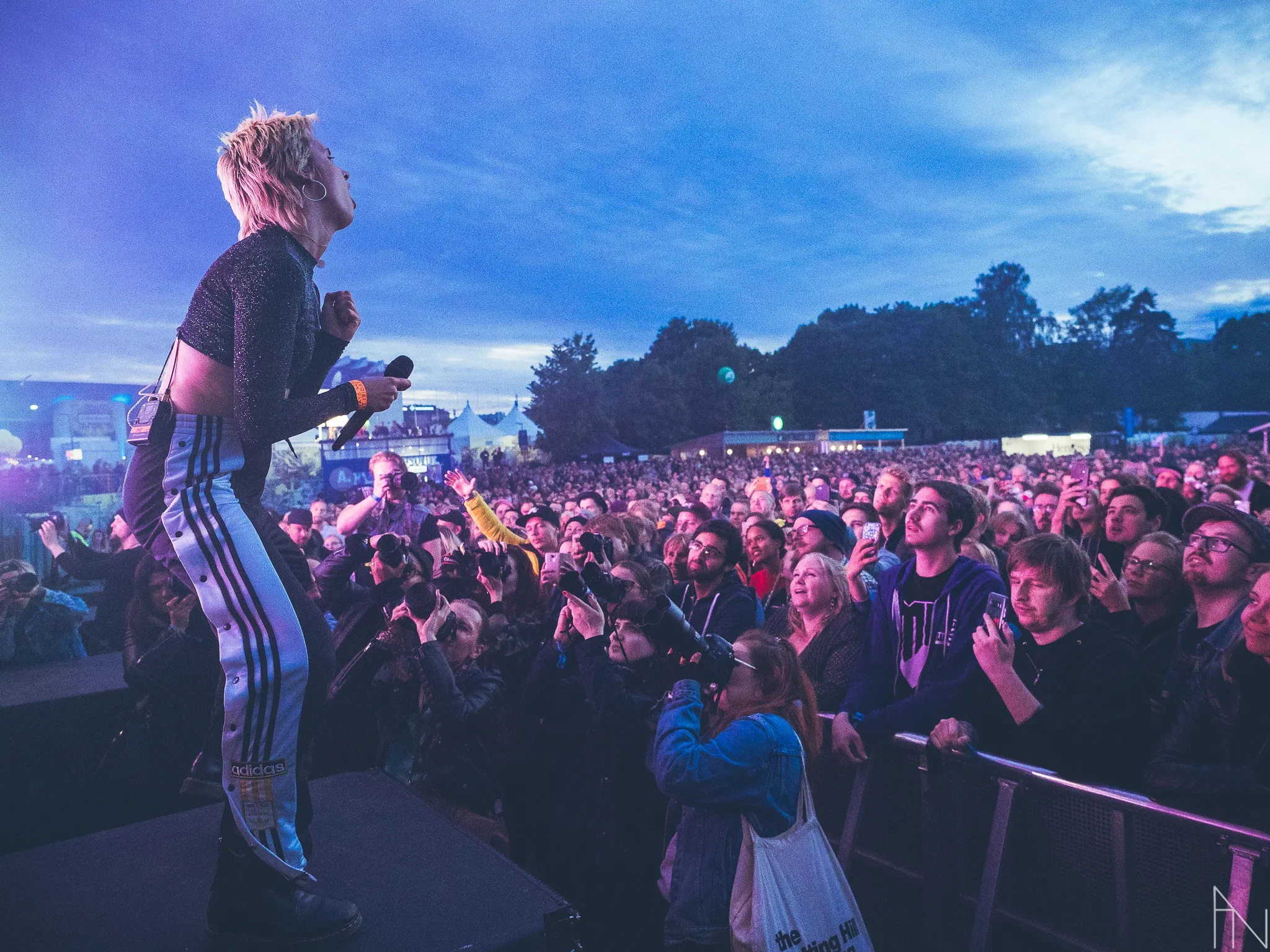 Arstisti laulamassa lavalla suuren yleisön edessä ulkotapahtumassa auringonlaskun aikaan.