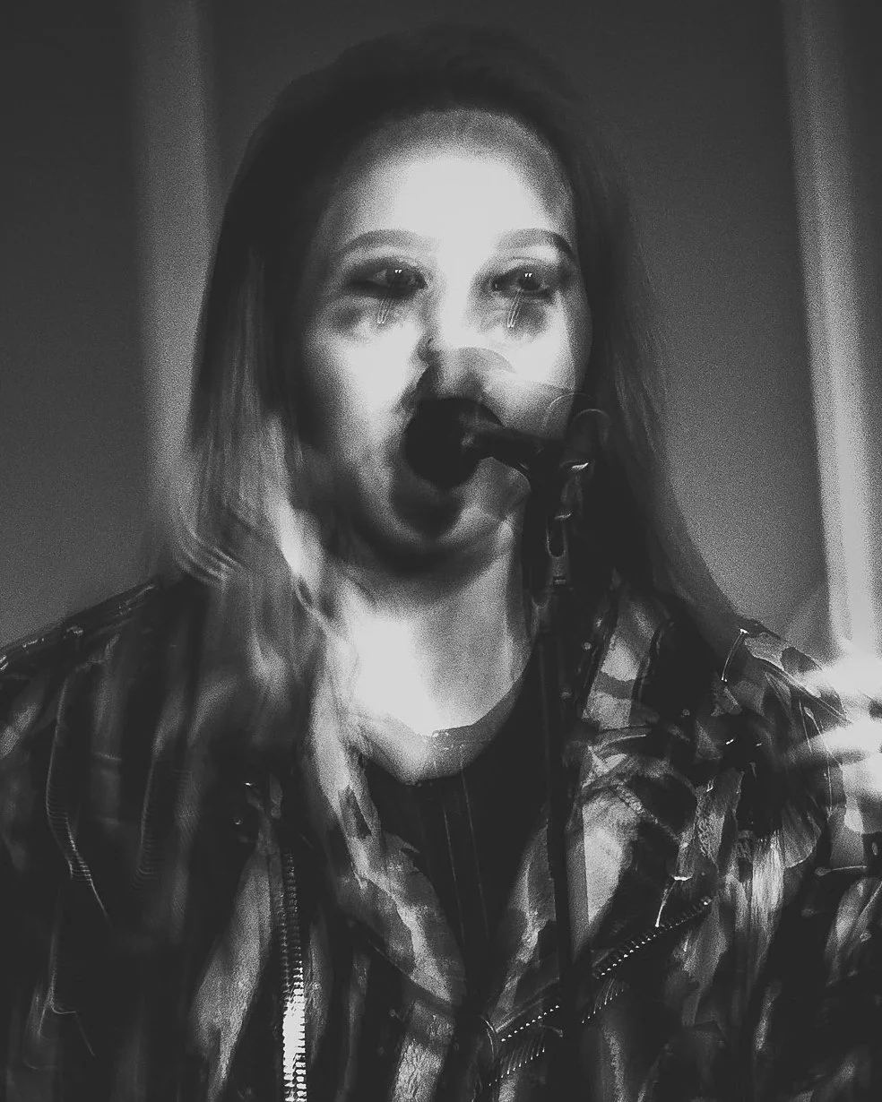 Mustavalkoinen kuva naisesta, joka laulaa mikrofonin edessä ja kyyneleet silmissä.