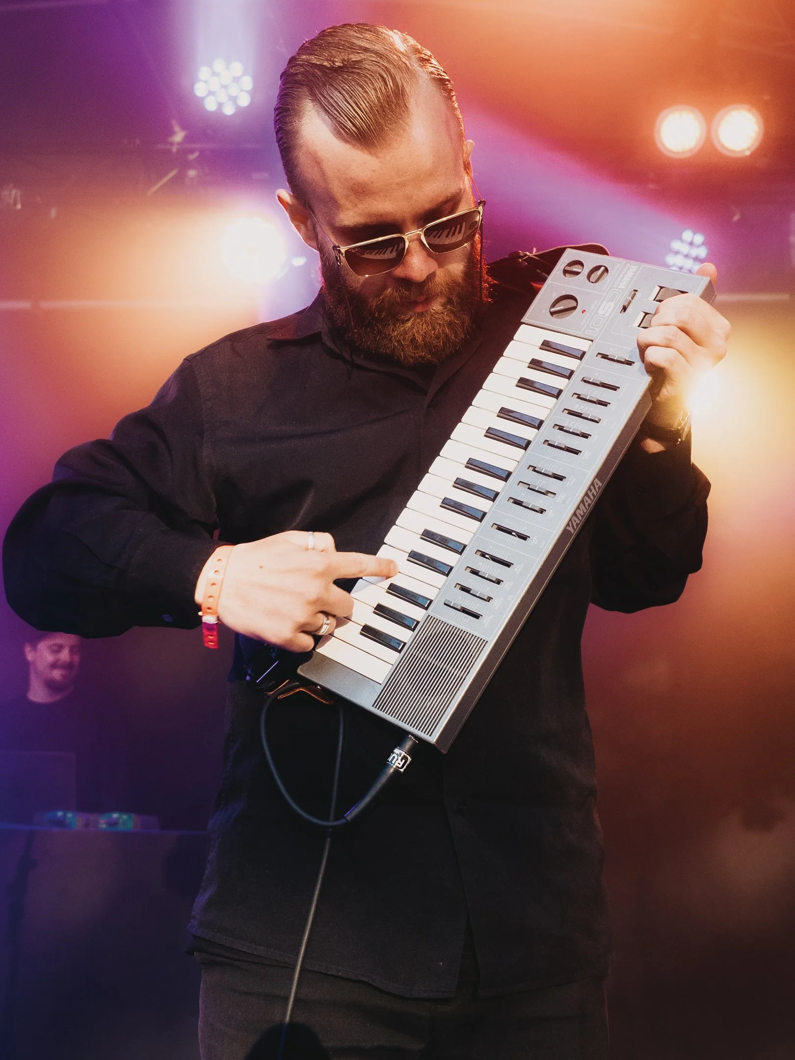 Mies soittaa Yamaha-syntetisaattoria ja tanssii vilkkaan valaistuksen alla. RIP Tuuttis, RIP Tuuttimörkö.