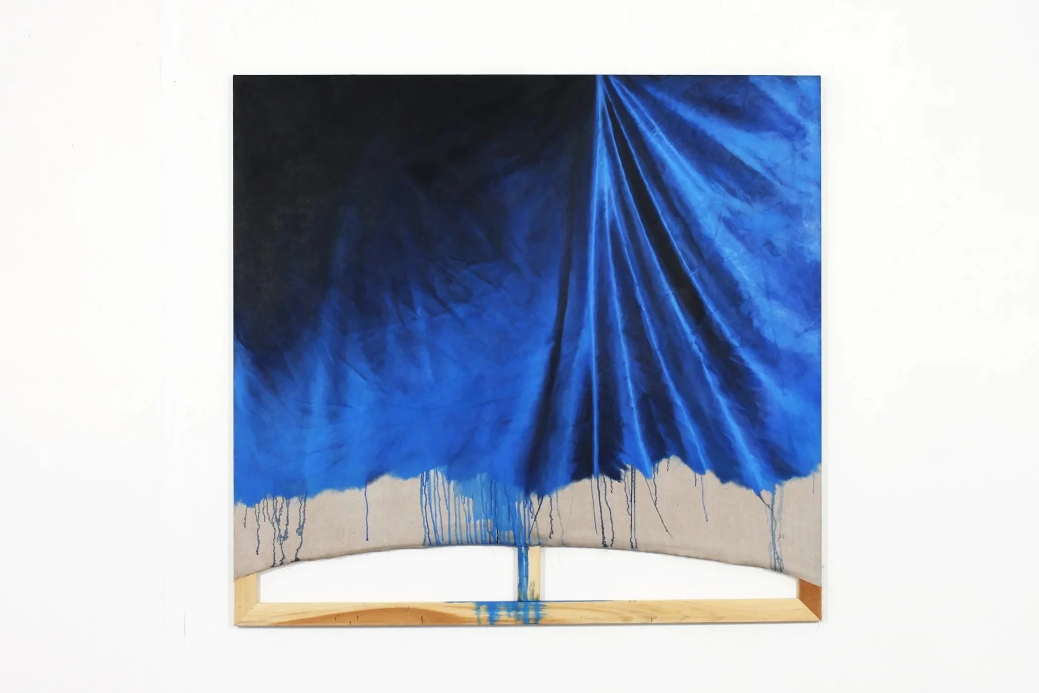 An abstract mixed media artwork featuring a vibrant blue fabric or paper with ruffled and dripping textures, mounted on a wooden frame.