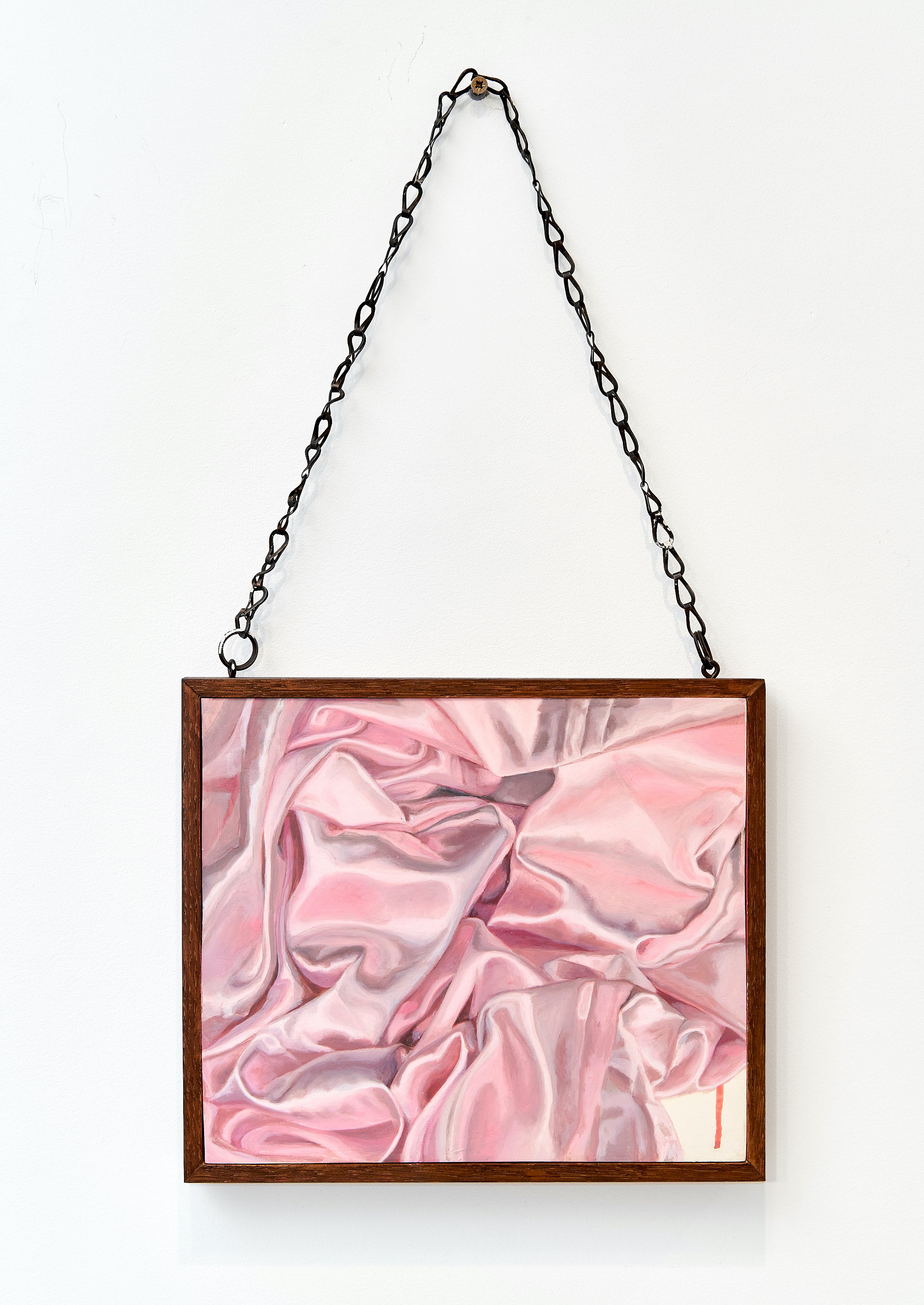 Painting with pink, white, and gray swirling patterns in a wooden frame, hanging from a chain on a white wall.