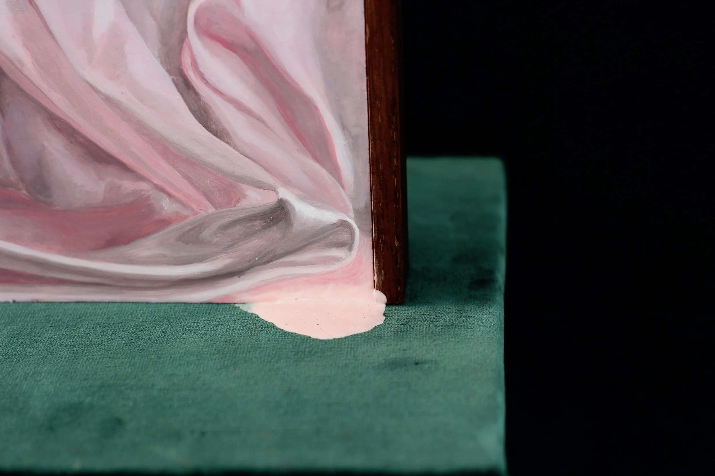 Close-up of a pink and white marble-patterned ceramic mug spilling pink liquid onto a green surface.