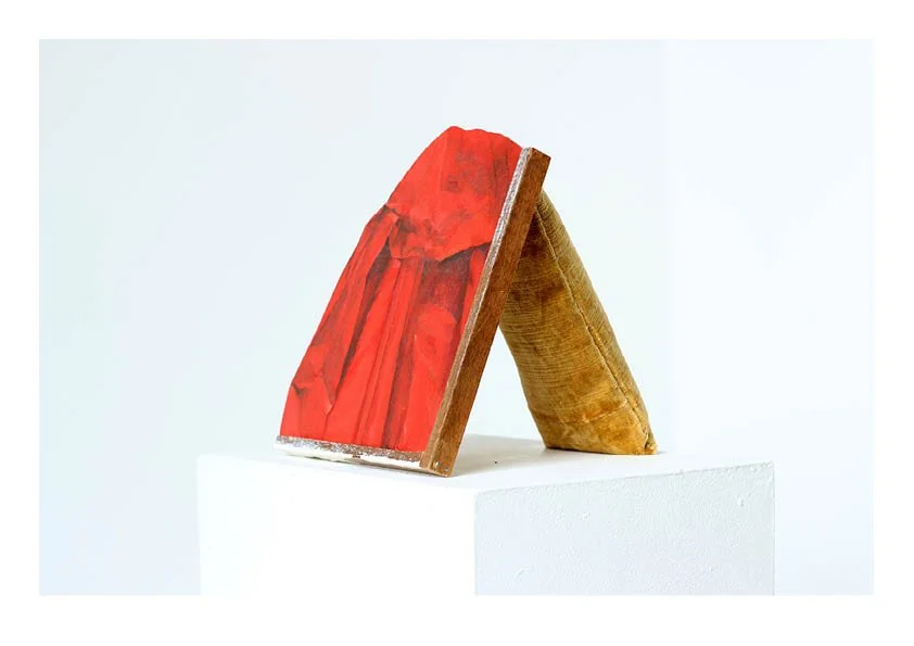 Mixed media sculpture resembling a kneeling woman in a red dress on a pedestal