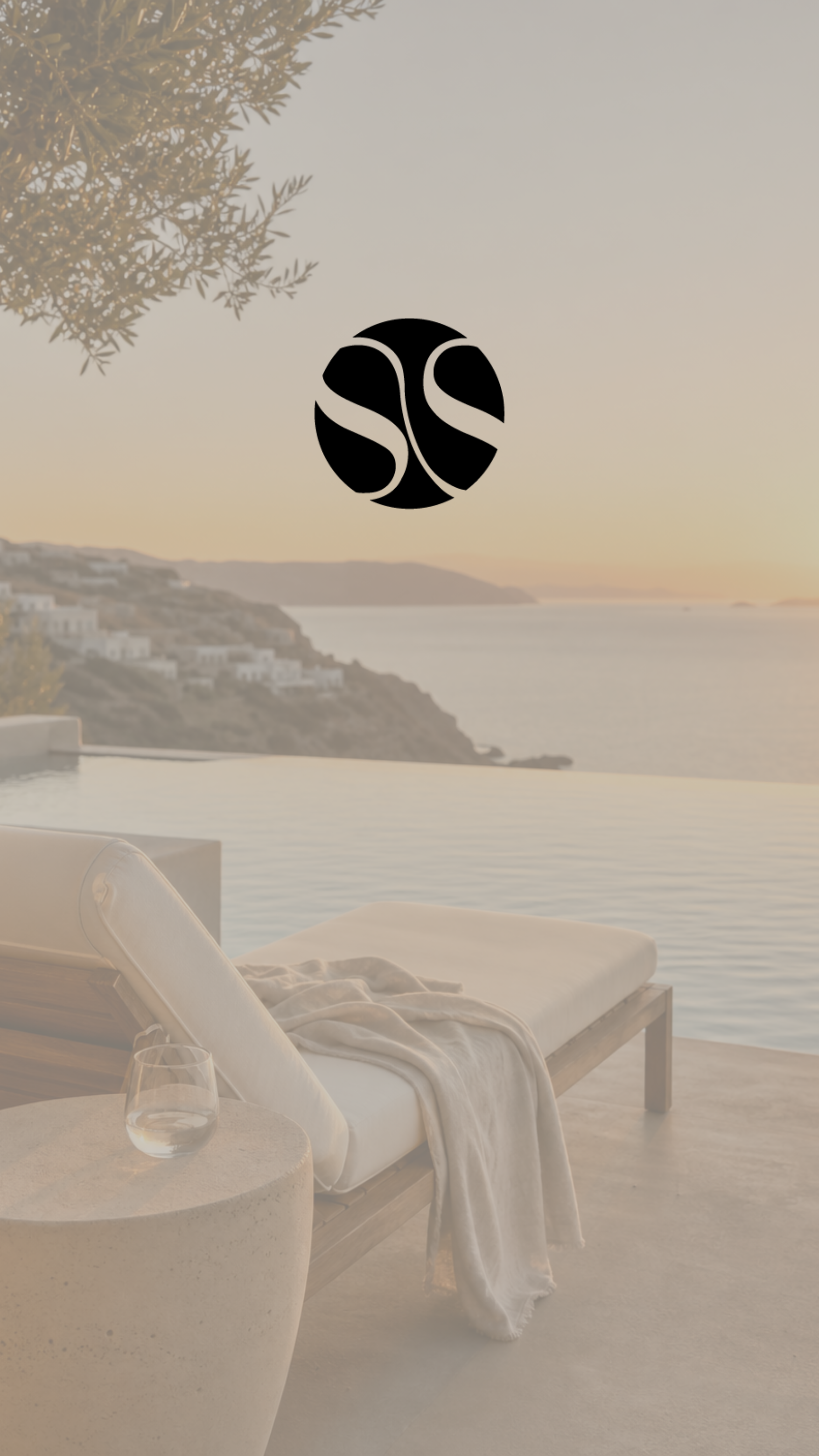 Een ligbed met witte lakens en een glas water, uitzicht op zee en witte gebouwen op een heuvel, zonsondergang in een luxe resort