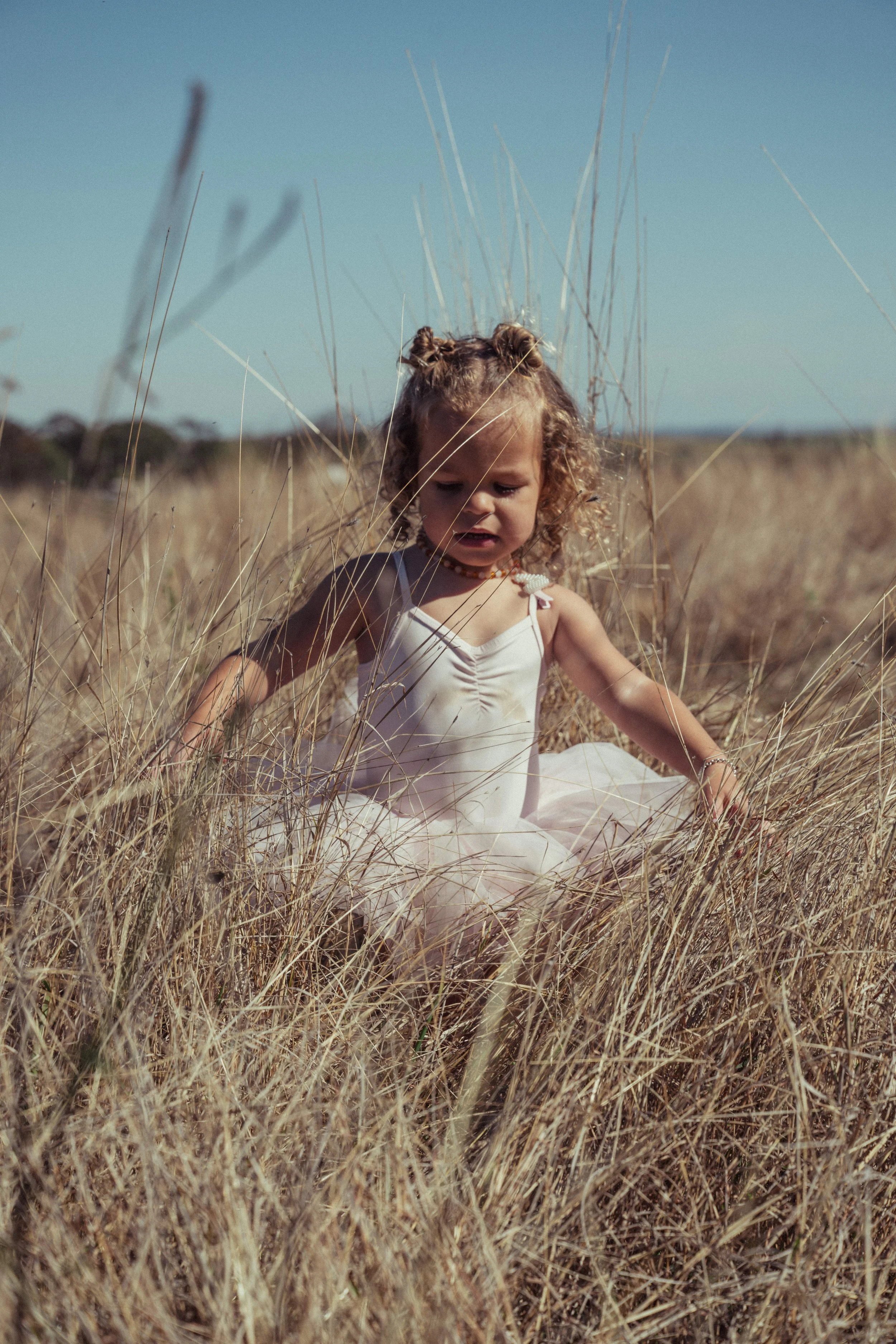 A young toddler dances in the grass in her ballet tutu. Scenic Rim farm life is the perfect photographic backdrop.