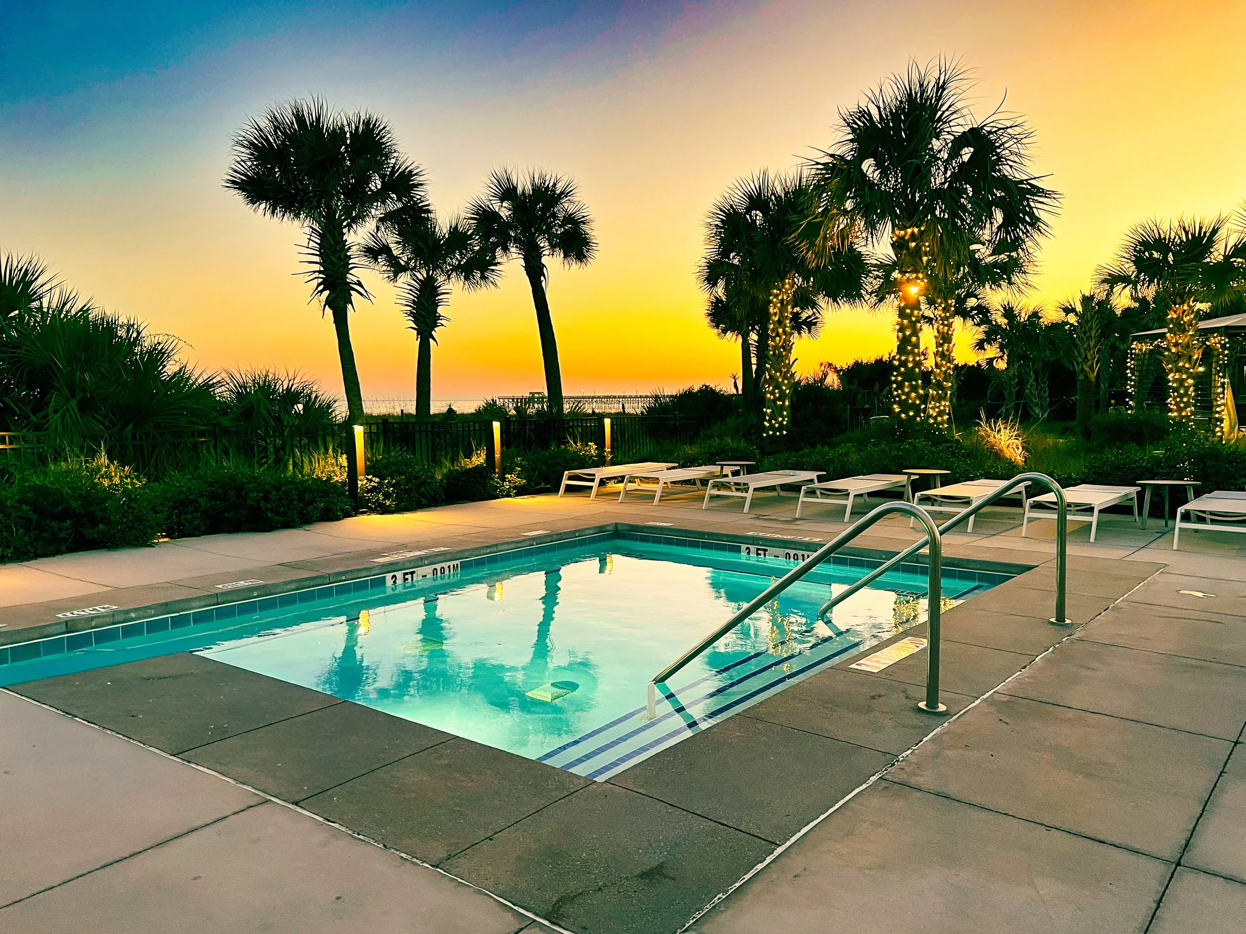 Beautiful hot tub with palm trees and blue and yellow sunset.