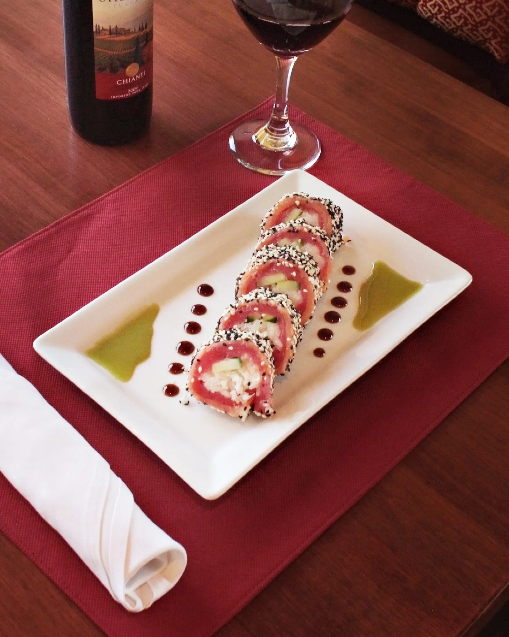 Sushi on a white plate with sauces artfully displayed on the side.