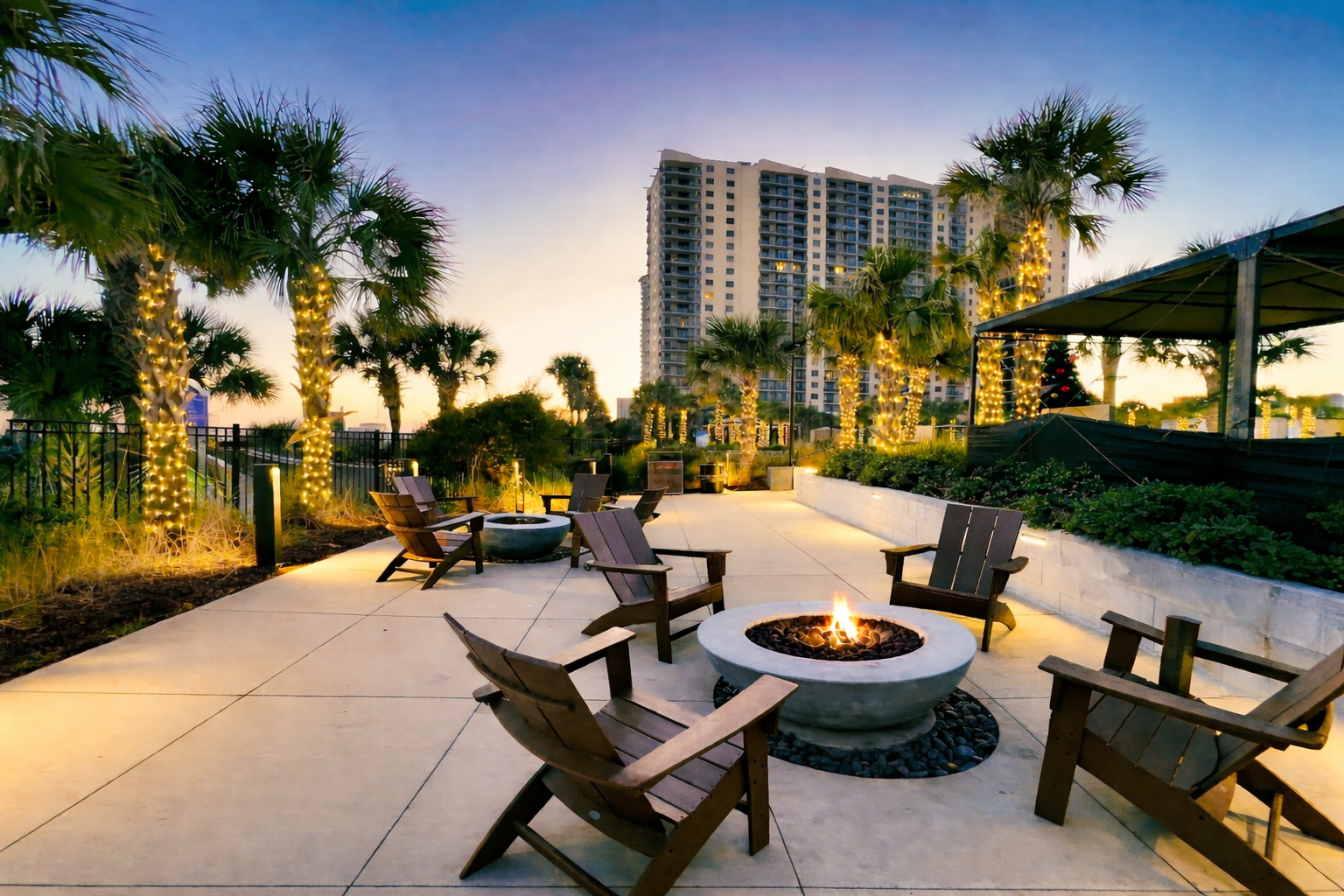 A fire in a a firepit with palm trees at dusk.
