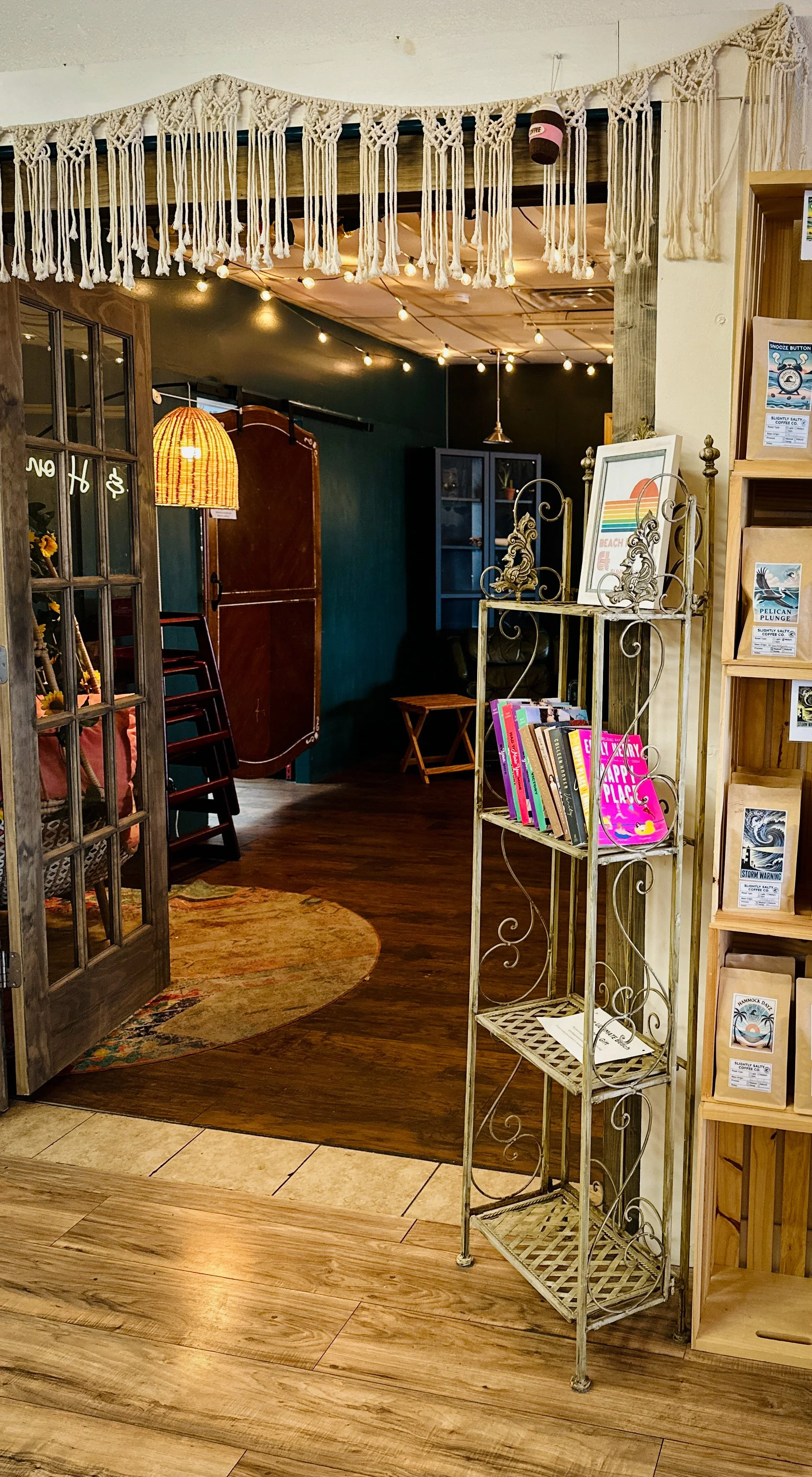Entrance to another room with a macramé fringe hanging from the ceiling and books on a shelf. 