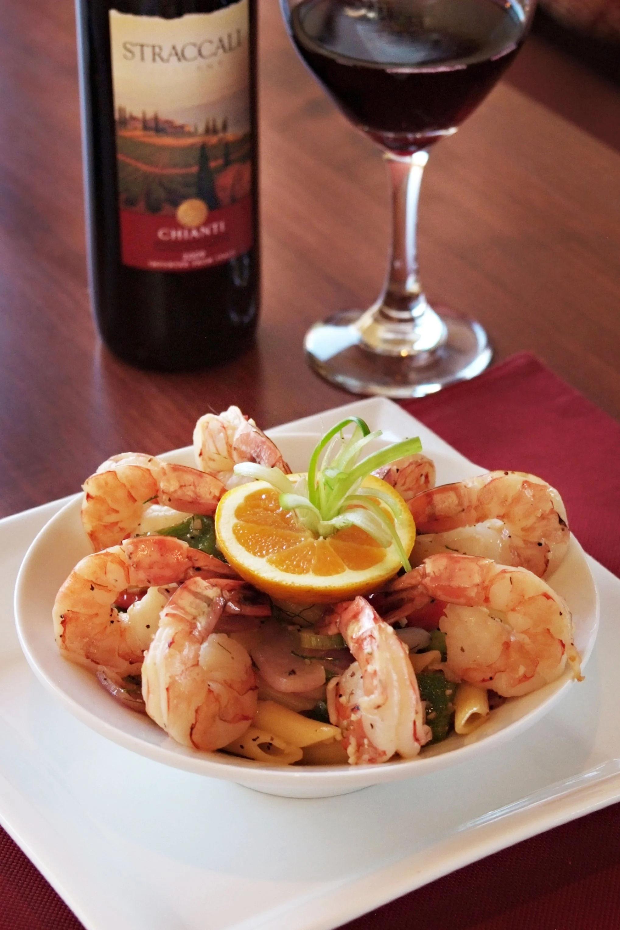 Shrimp cocktail with orange garnish and red wine.