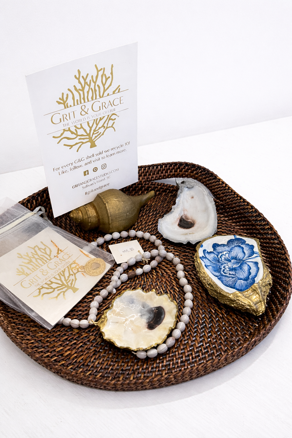 Grit and Grace oyster art and jewelry on a brown wicker plate.