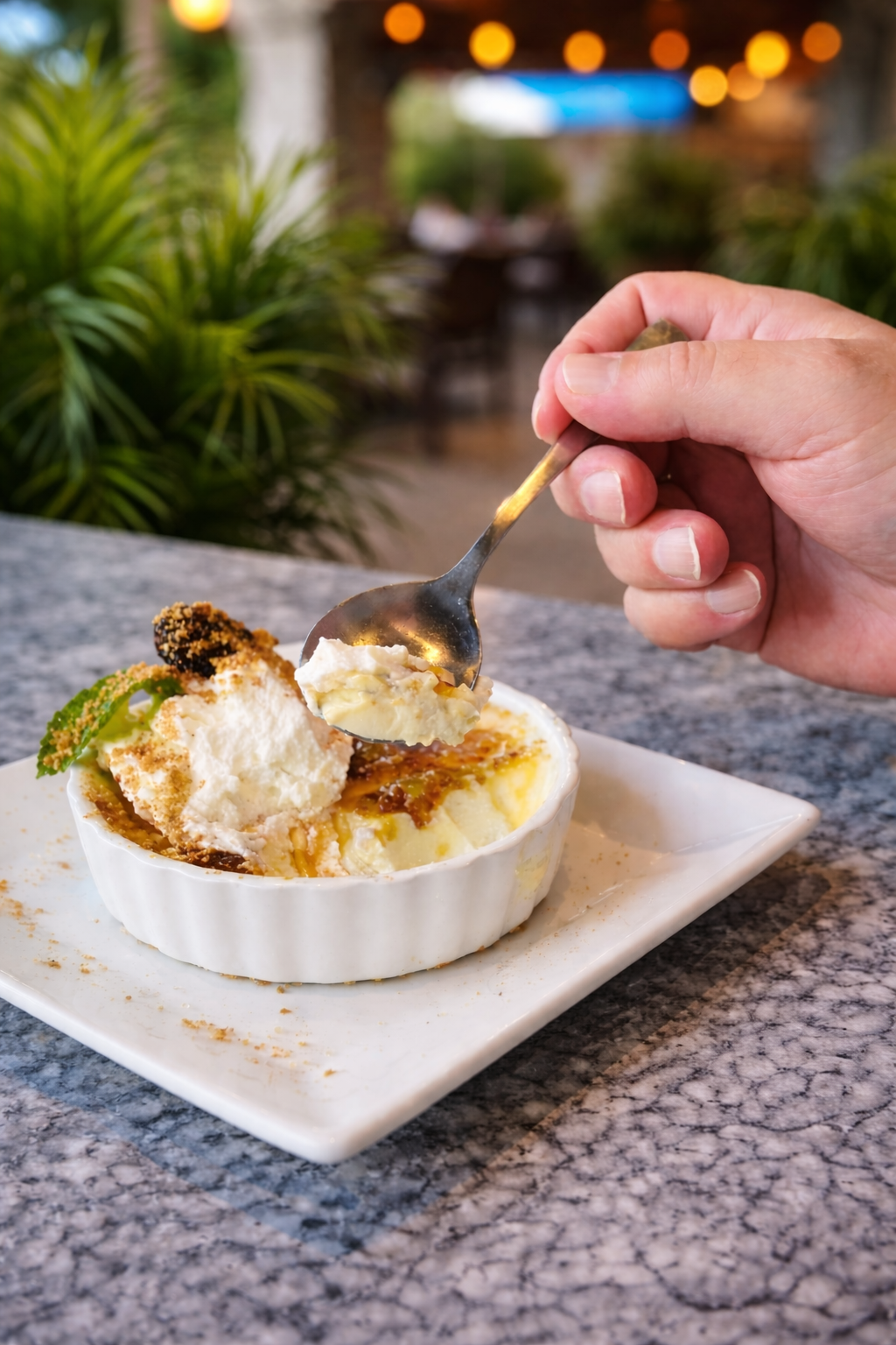 Crème brûlée with ice cream in a white ramakin and a person with a spoon dipping into it.
