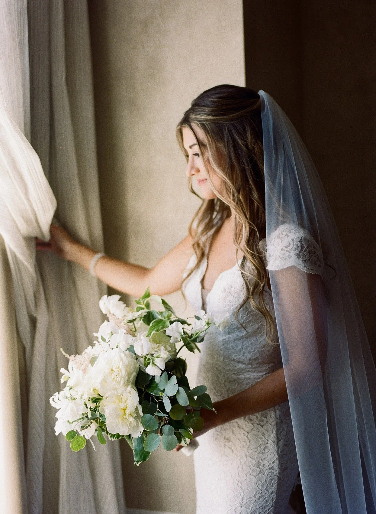 Bride looking out window on wedding day in Saratoga Springs NY