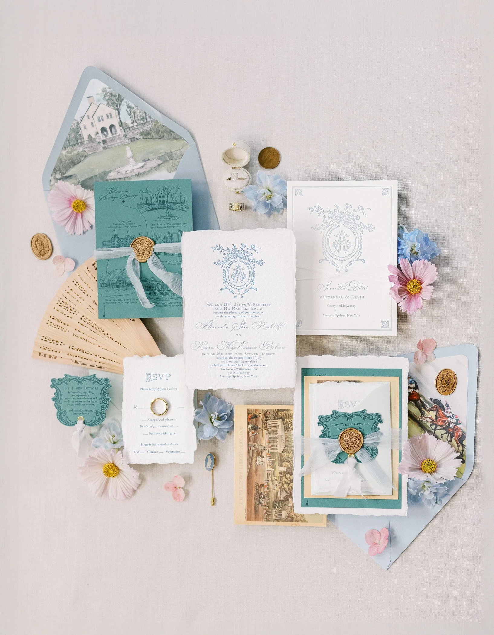 Flat lay of vintage wedding invitation suite with floral accents, RSVP cards, and decorative elements on a light pink surface.