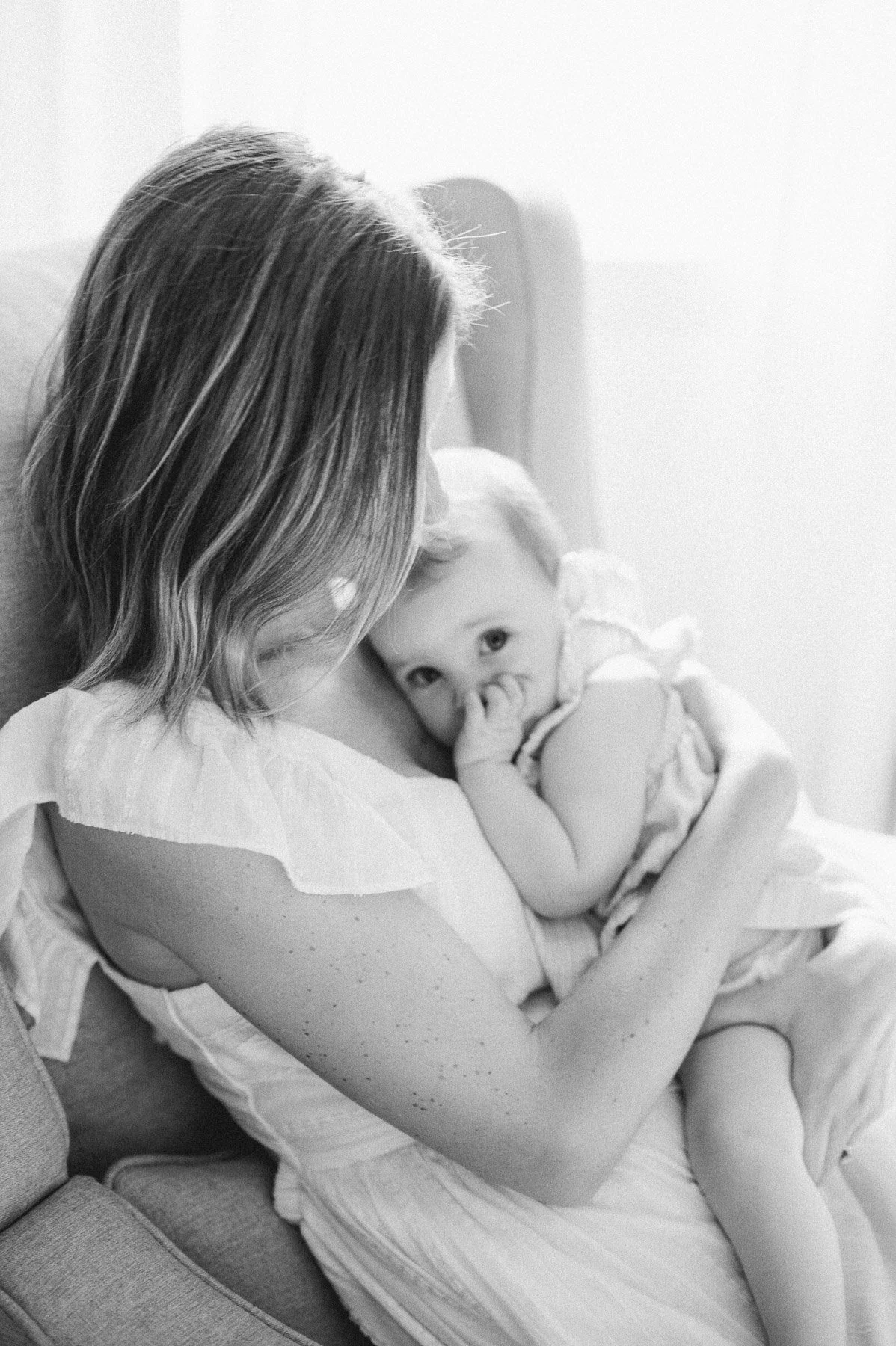 A woman breastfeeding a baby in black and white.