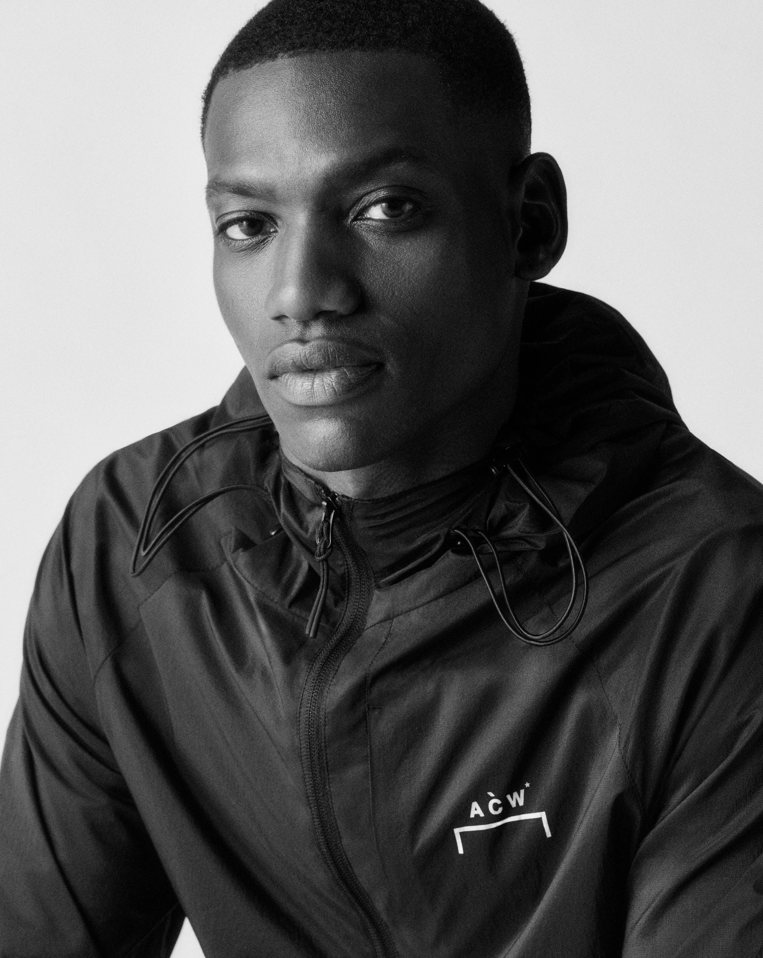 ASOS Menswear New Season Fashion Campaign. A person with dark skin and a short hairstyle wearing a black A Cold Wall jacket, looking at the camera with a neutral expression.