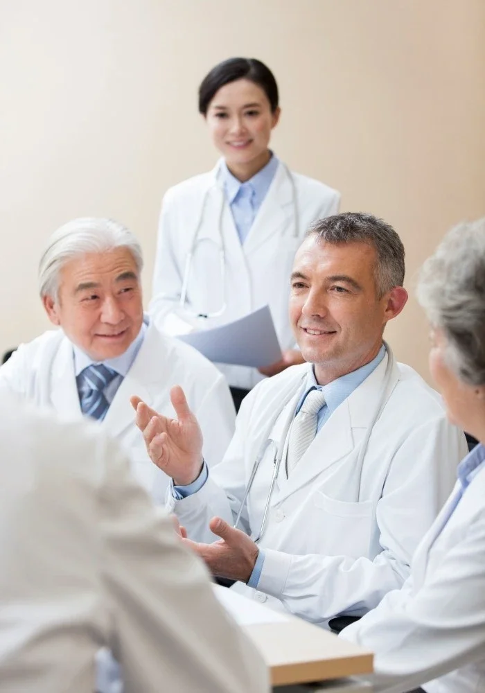 Medical team meeting in a hospital, with doctors and a nurse discussing.