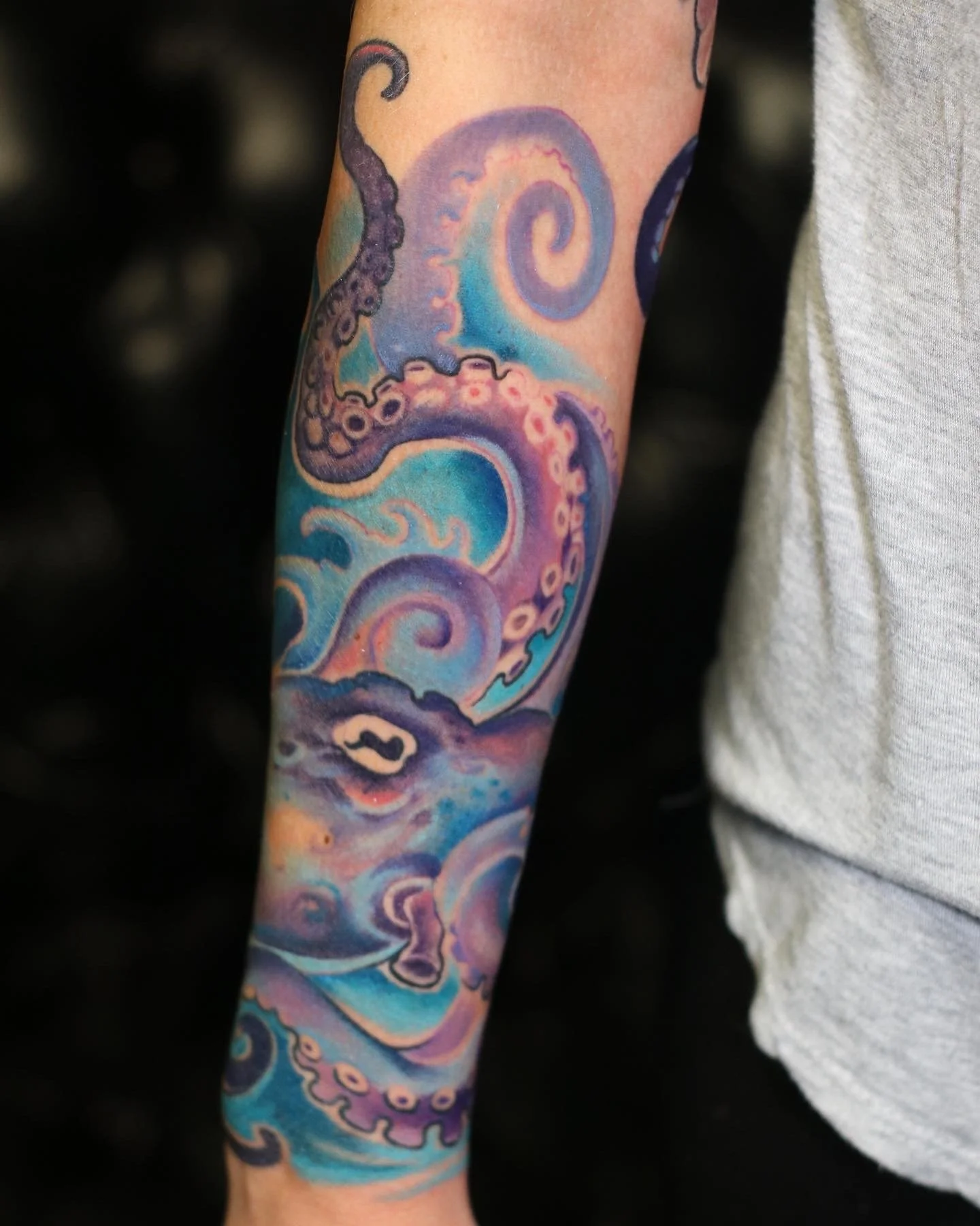 Colorful tattoo of an octopus and waves on a person's arm.