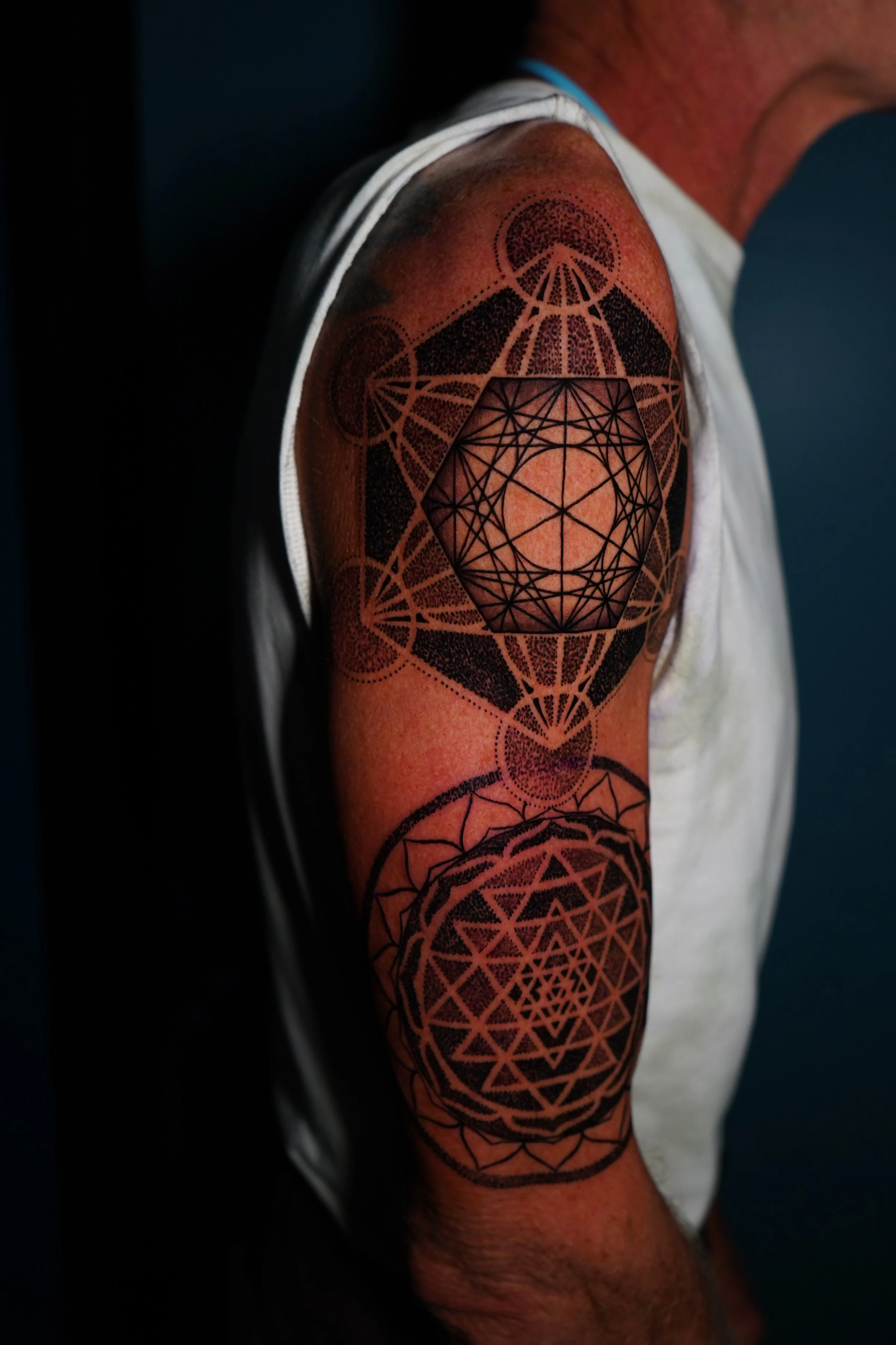 Tattoo sleeve featuring geometric patterns and shapes on a person’s upper arm.