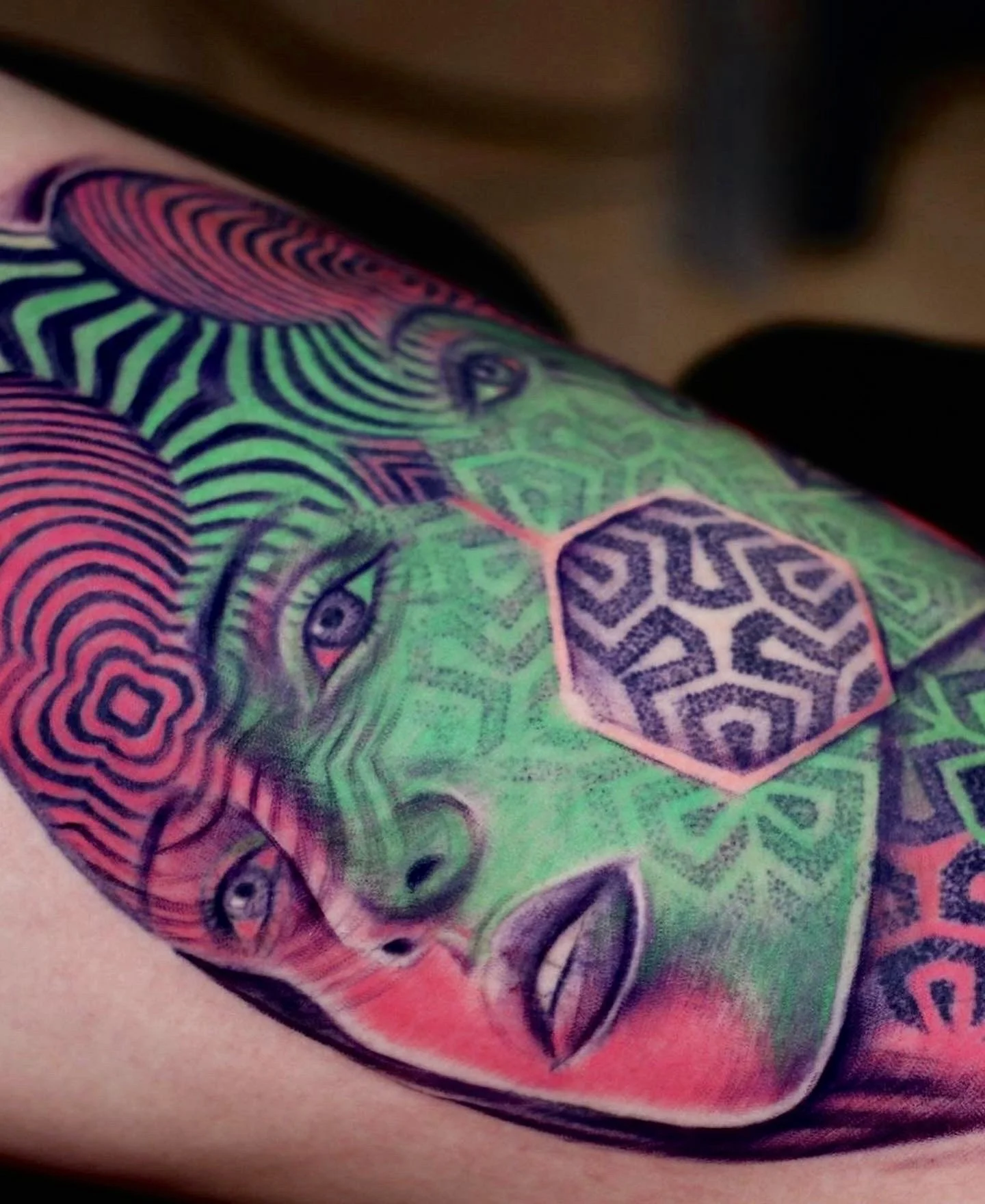 Colorful tattoo of a woman's face with geometric and abstract patterns in various vibrant colors.