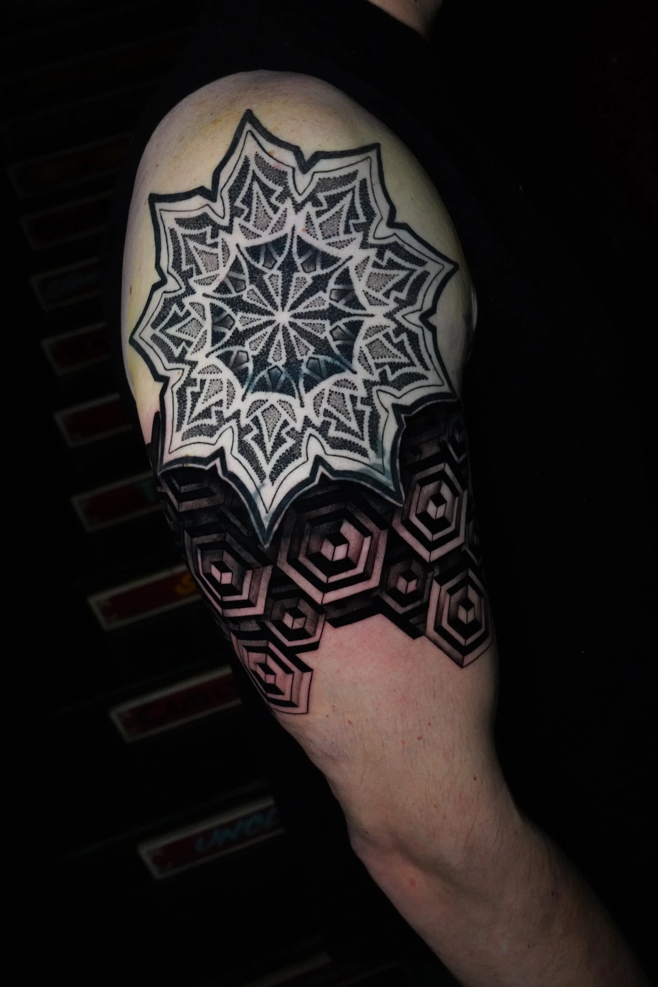 Tattoo of a spider web and geometric patterns on a person's upper arm.