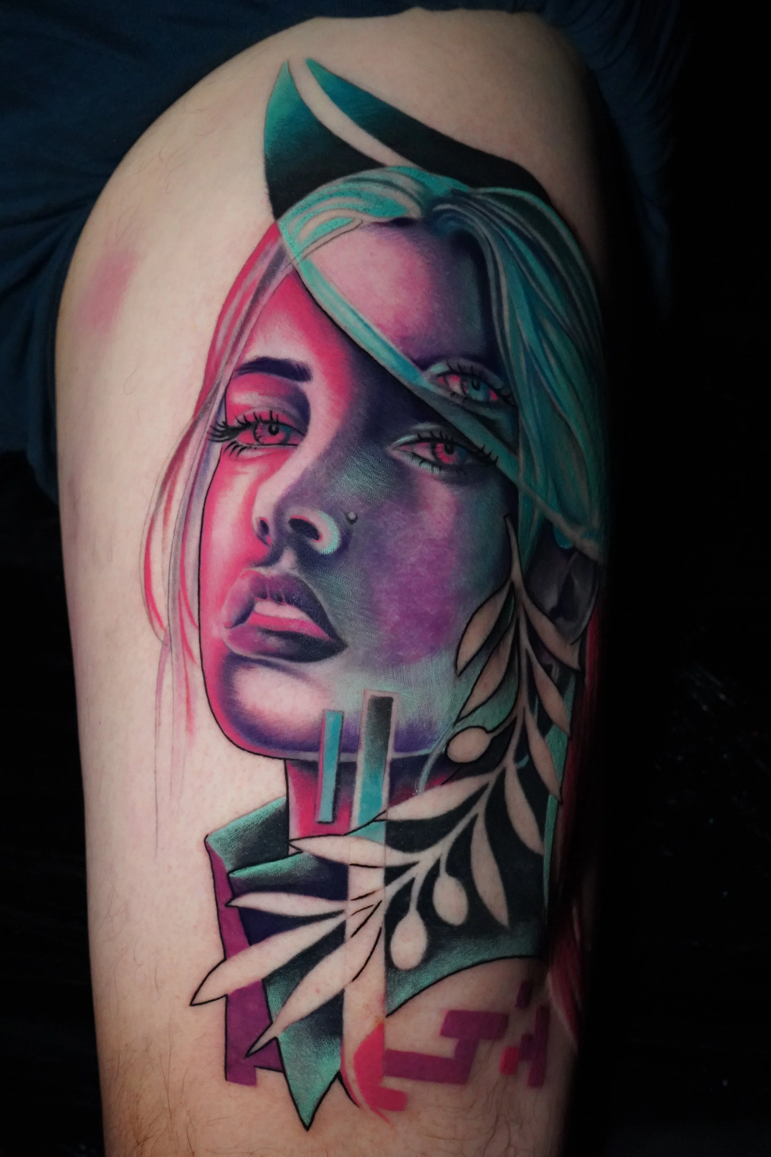 Colorful tattoo of a woman's face with teal hair surrounded by leaves on an arm.