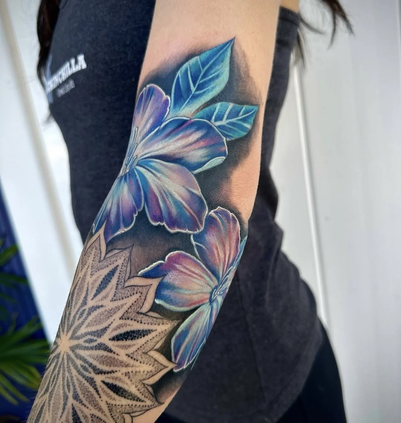 A colorful tattoo of two large butterflies with blue and purple wings and green leaves on a person's arm.