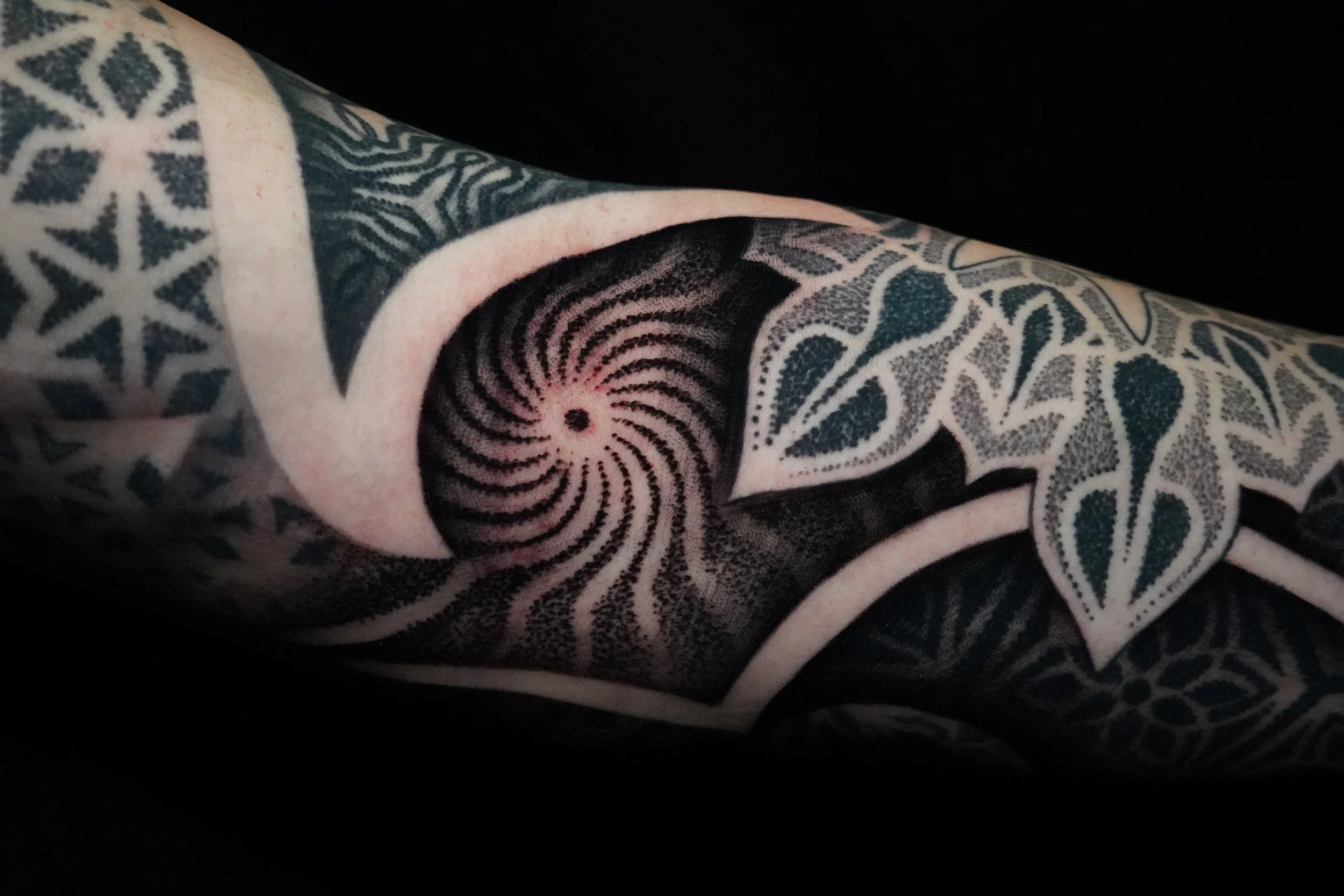 Close-up of a black and white tattoo sleeve with geometric and abstract designs.