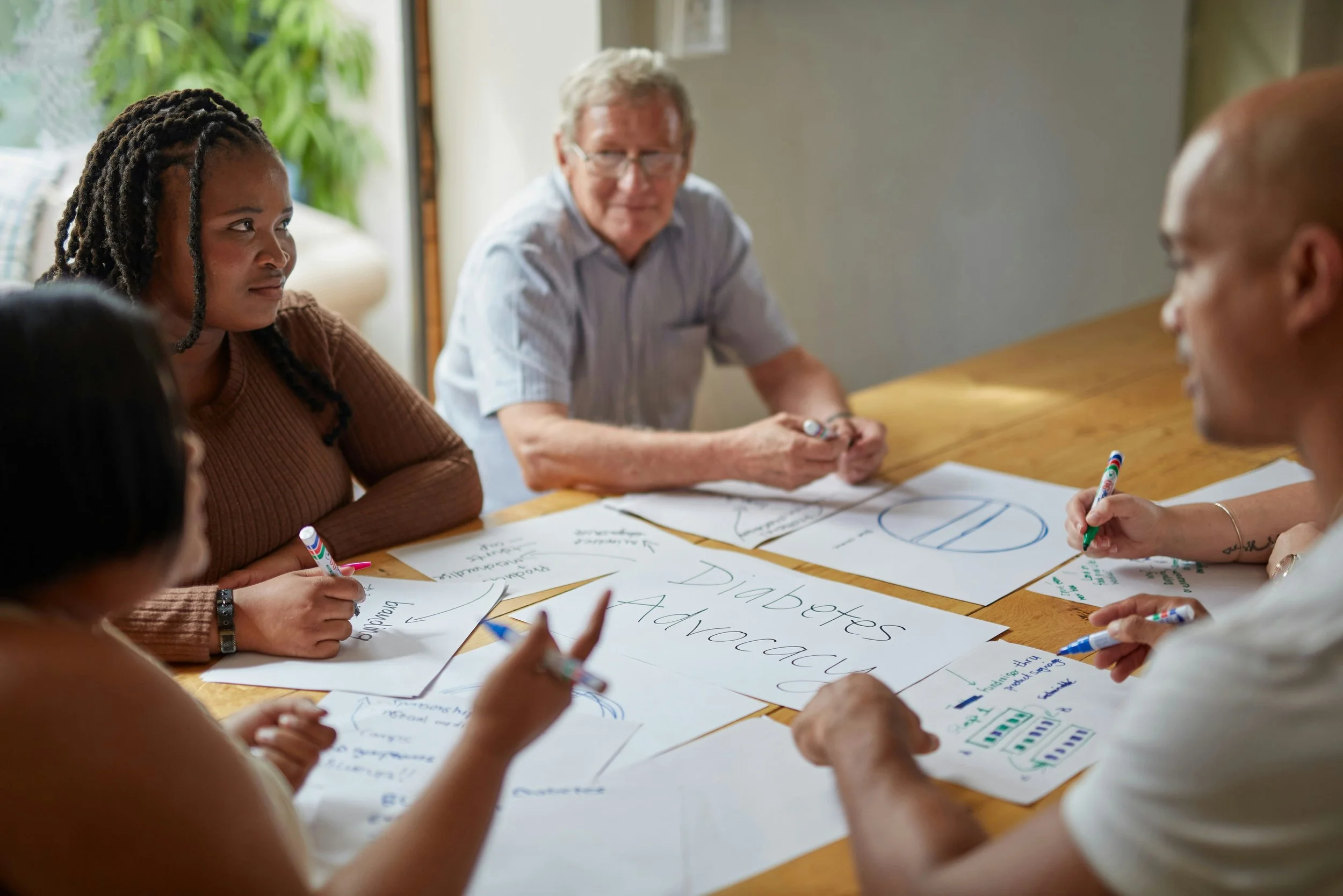 Colleagues taking notes around a table during a project meeting.