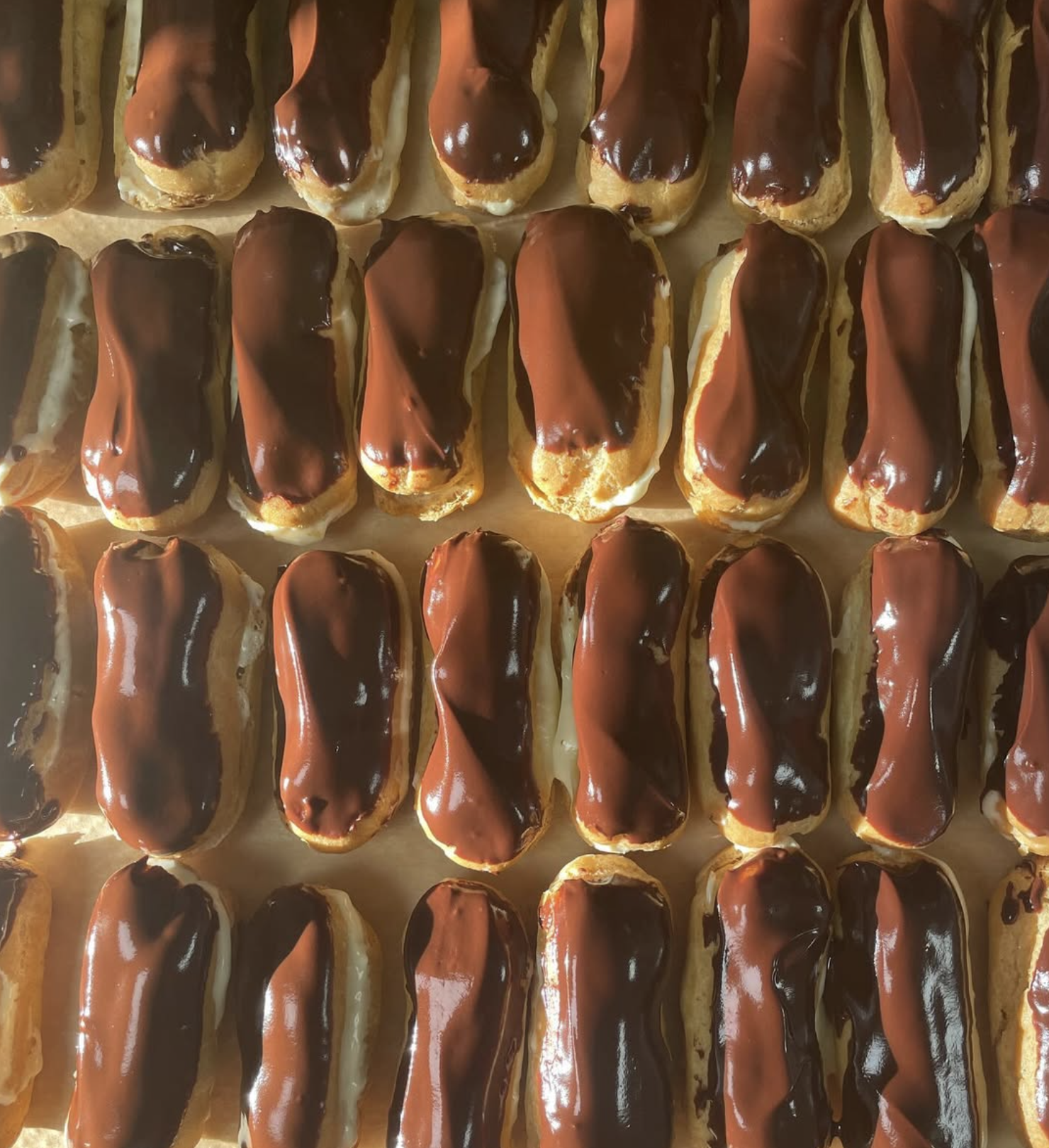 A tray of eclairs topped with chocolate glaze.