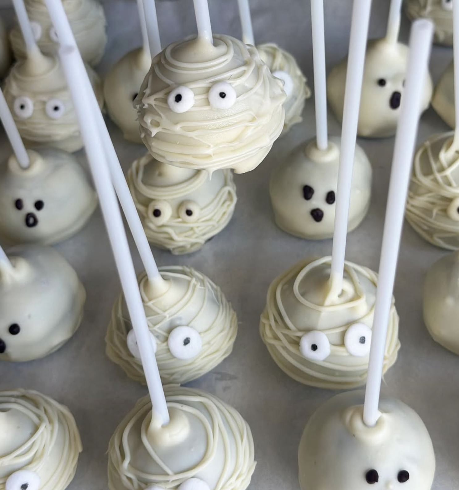 White cake pops decorated with eyes and mouth to resemble cute cartoon characters.