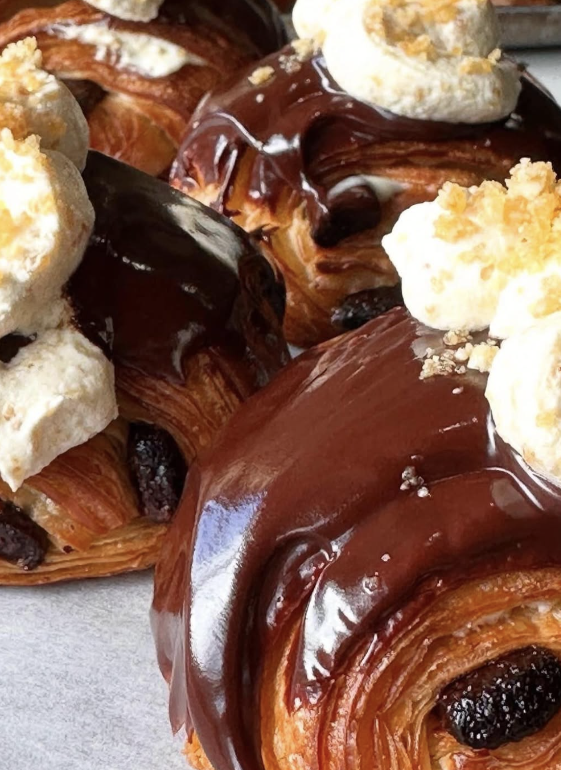 Close-up of caramel pastries with chocolate glaze and cream topping.