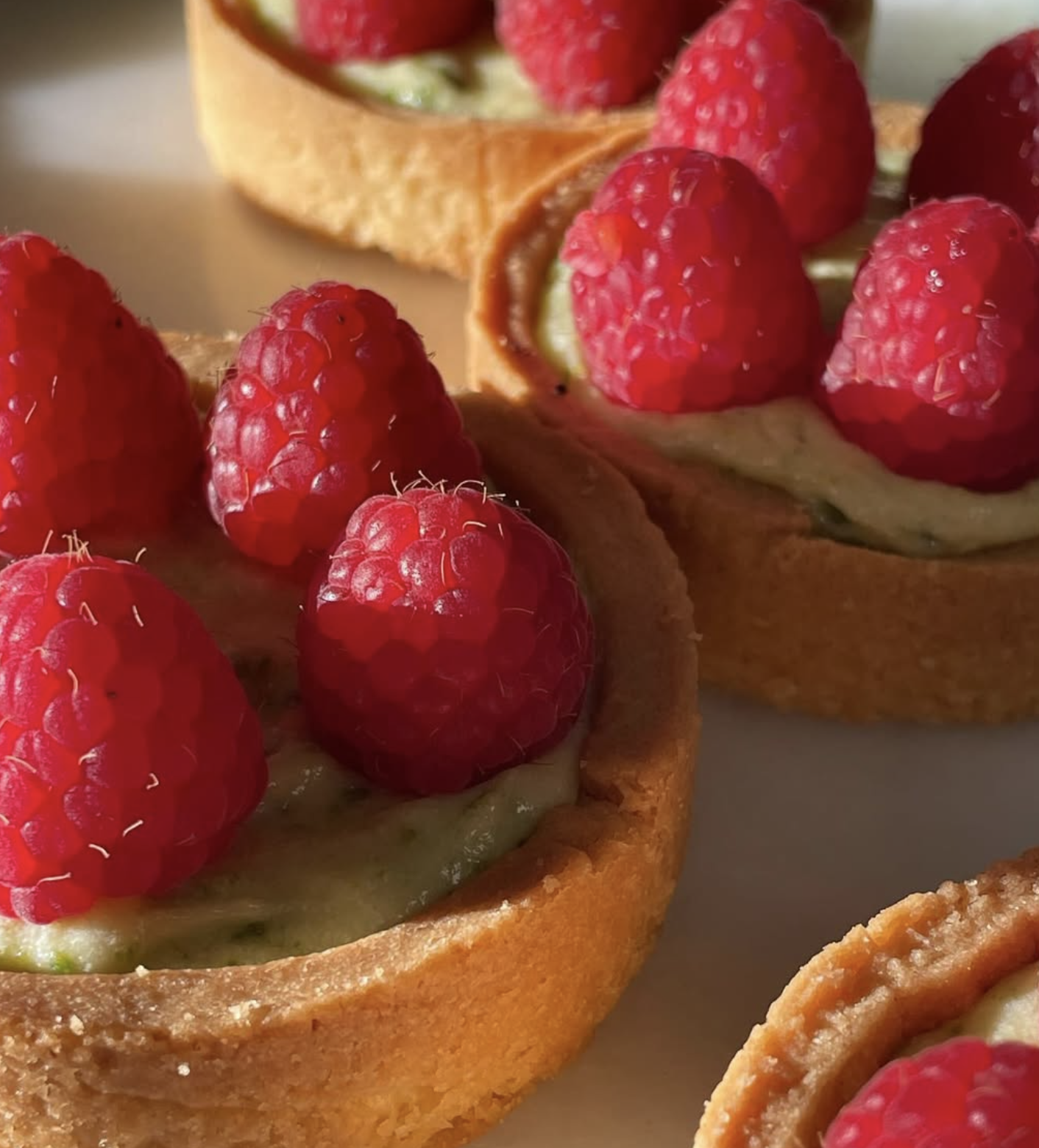 Close-up of raspberry tartlets with fresh raspberries on top.
