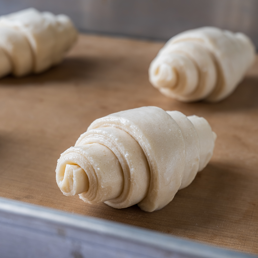 Raw croissants on a baking sheet.