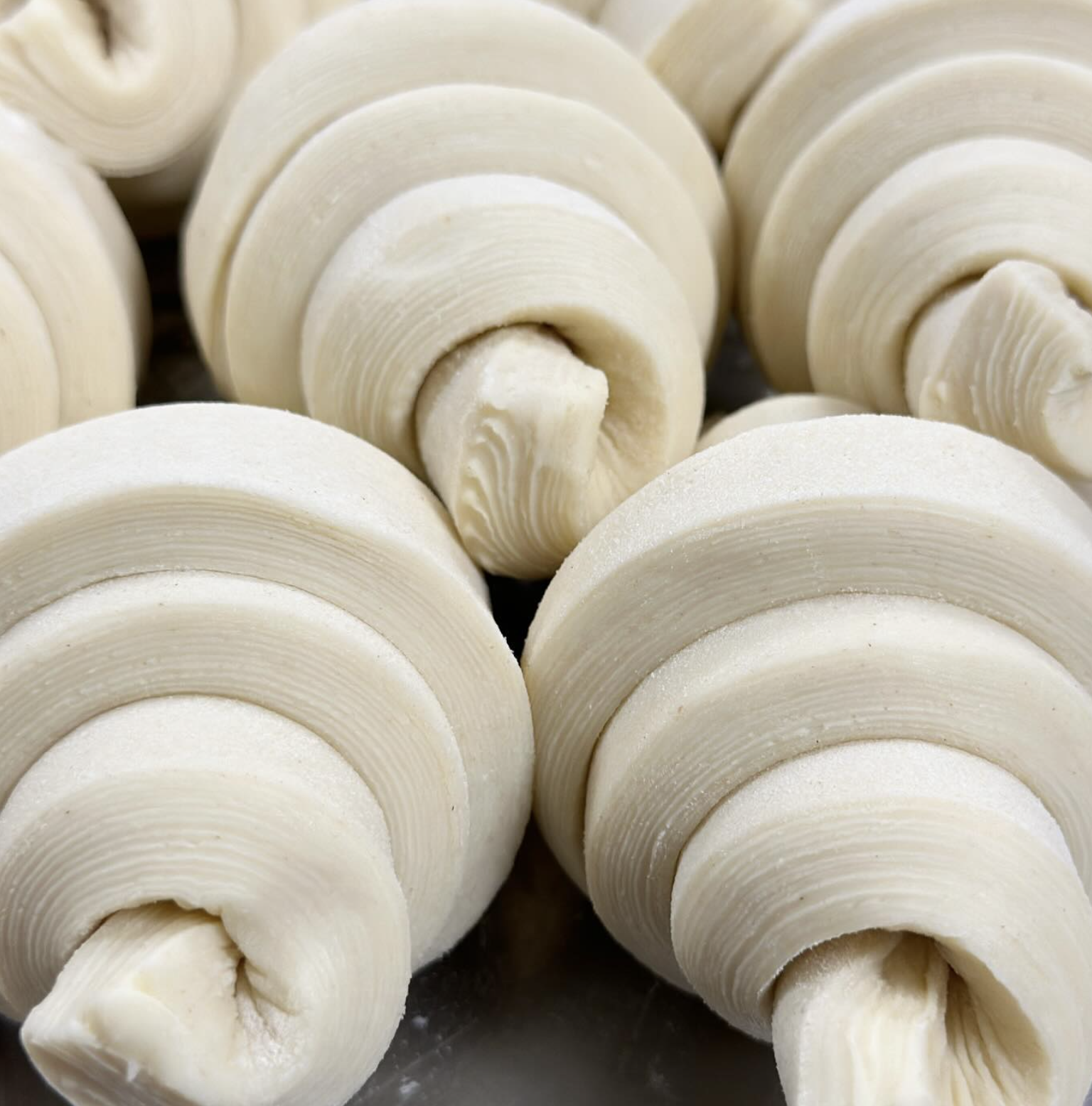 Close-up of uncooked croissant dough rolls.