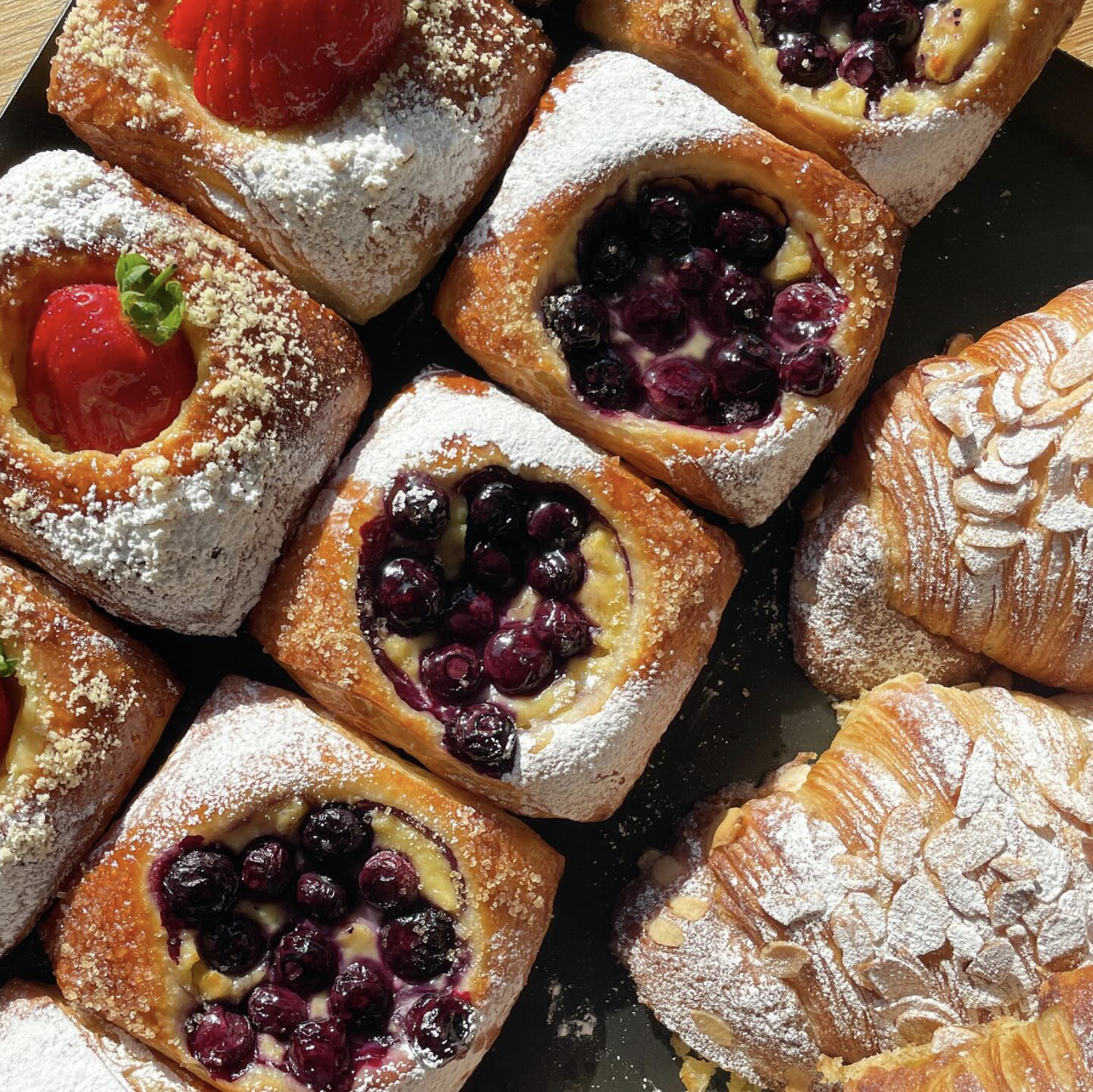 Assorted pastries including fruit-filled Danish and almond croissants