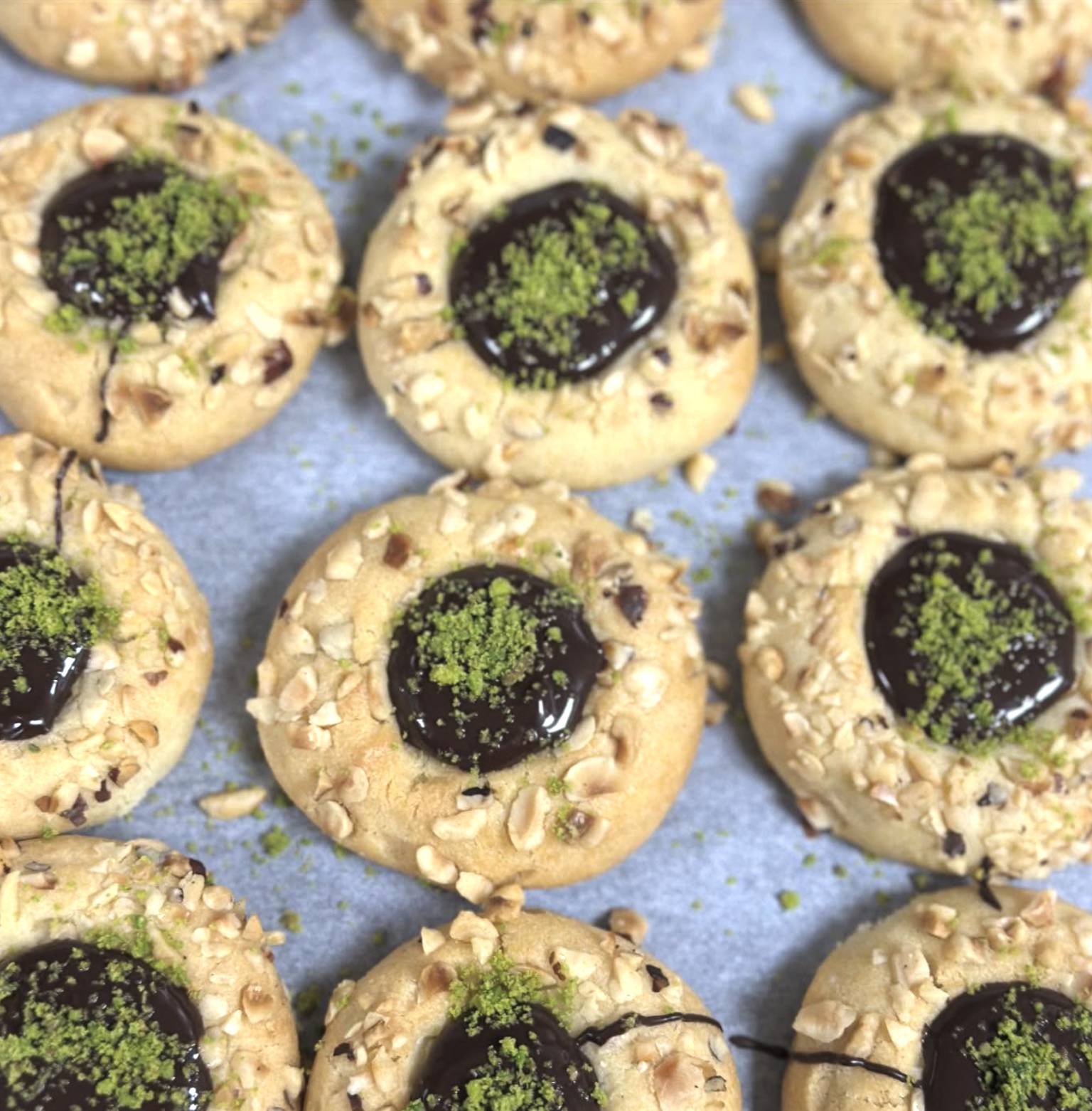 Cookies with chocolate and green sprinkles on top, surrounded by crushed nuts.