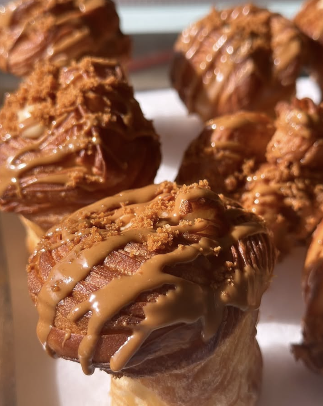 Close-up of bacon-wrapped jalapeno poppers topped with caramel sauce and crumbled crumbs.
